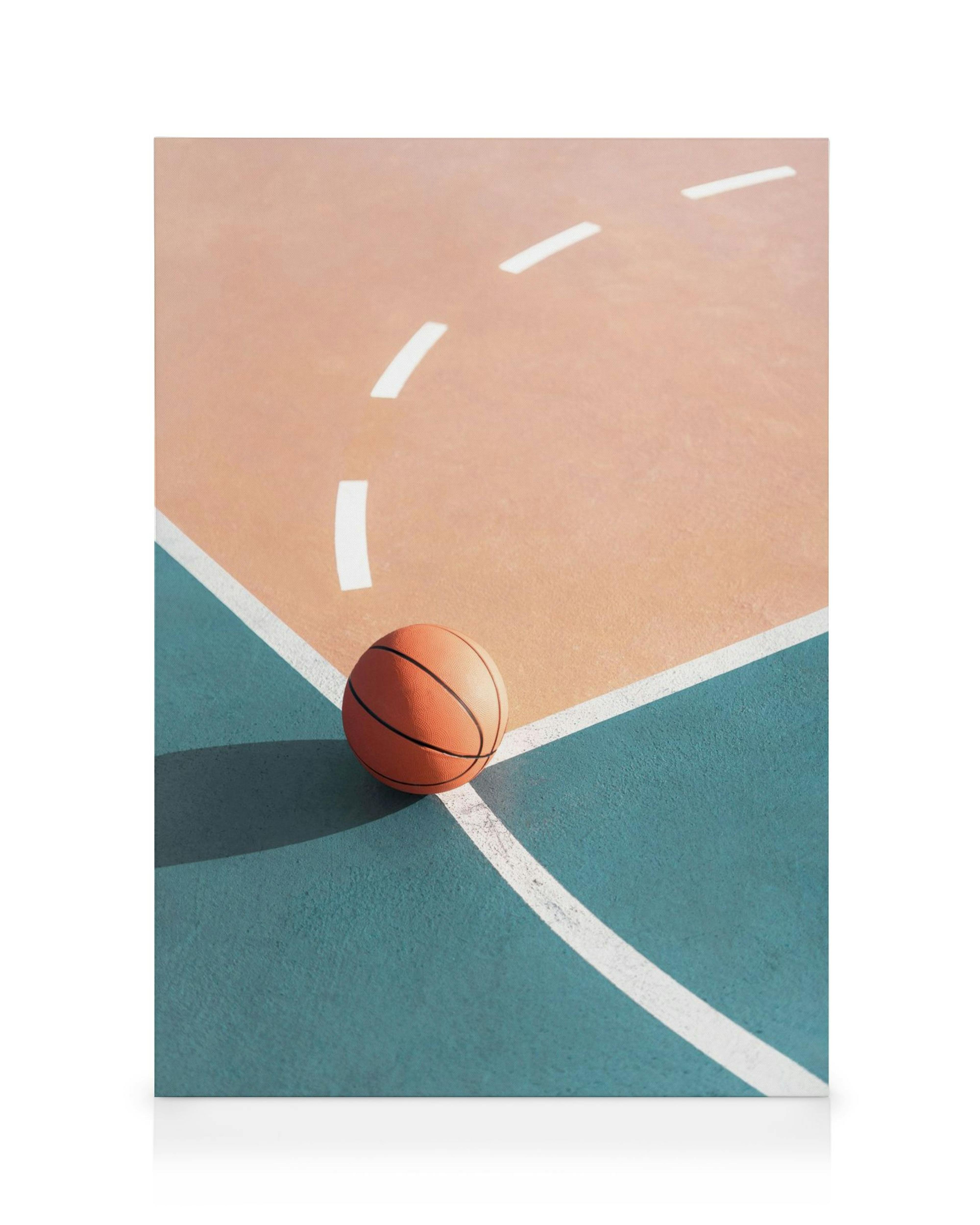 Orange basketboll på en persikofärgad och turkos basketplan med vita linjer och tydliga skuggor från solljus.