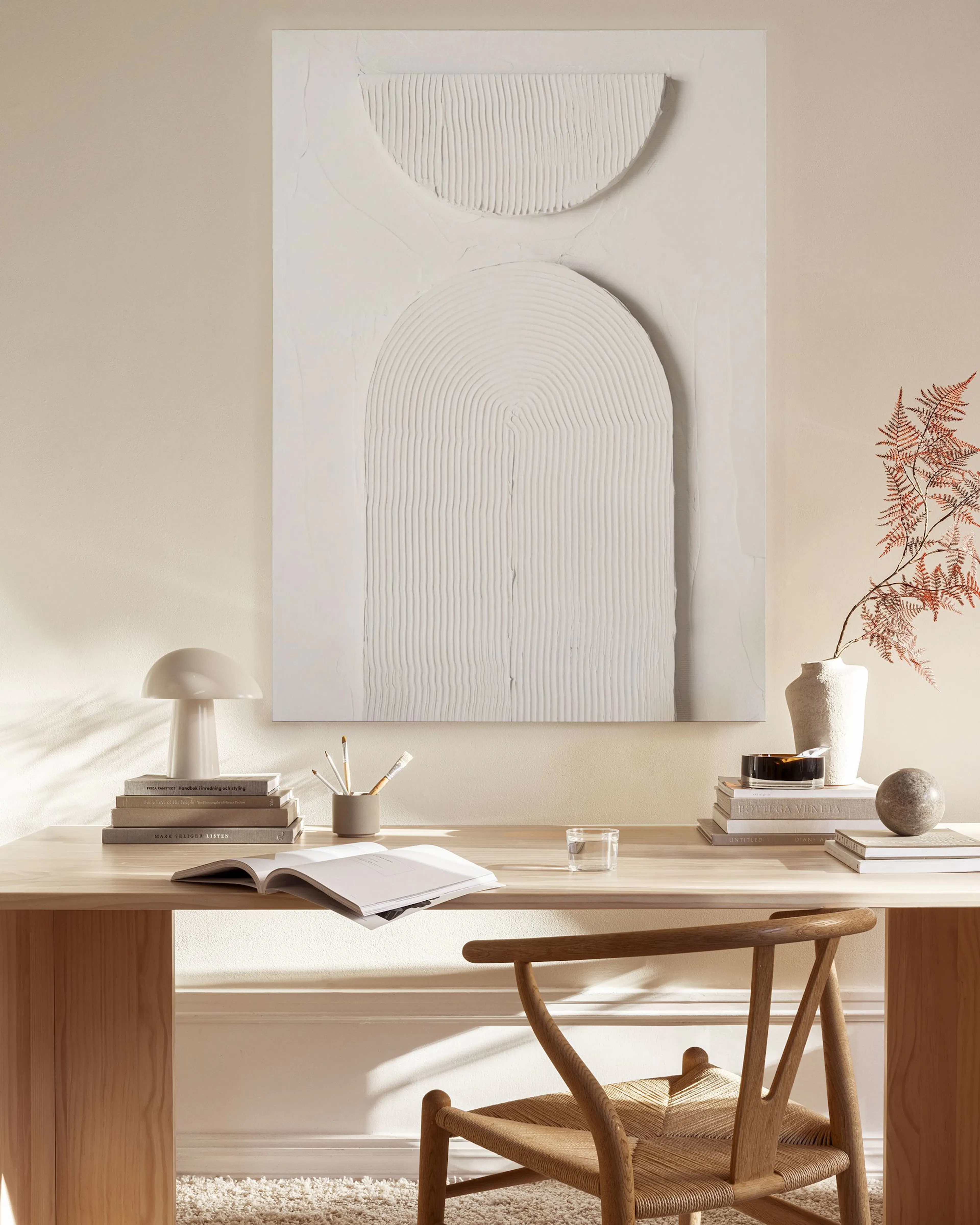 Strukturiertes Leinwandbild mit halbkreisförmigen weißen Reliefs in einem minimalistischen Wohnzimmer.