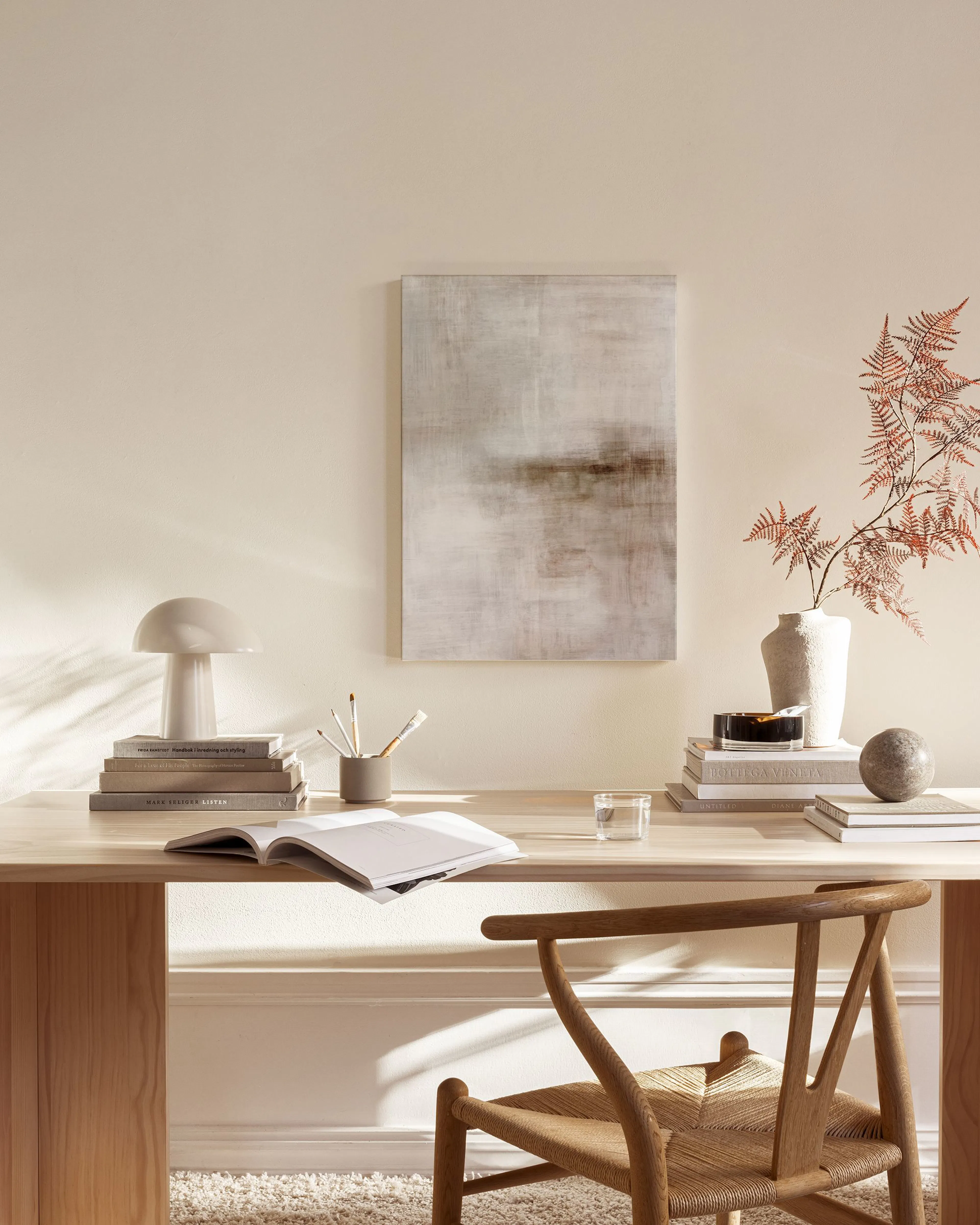 Canvas met wazige, abstracte vormen in bruin- en grijstinten, hangend in een neutrale woonkamer.