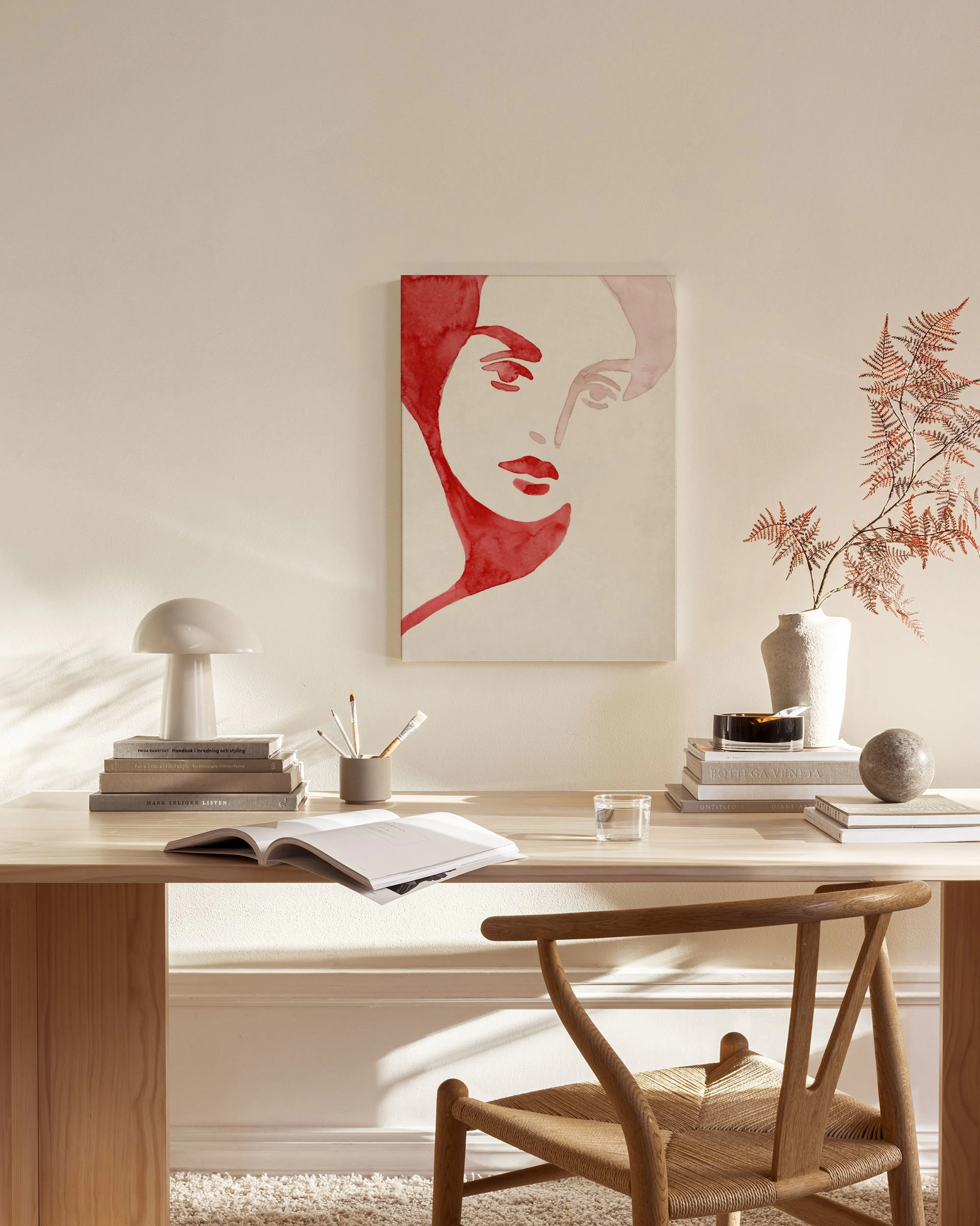 Canvas met rood waterverfportret van een vrouw, hangend boven een houten dressoir in een minimalistische kamer.