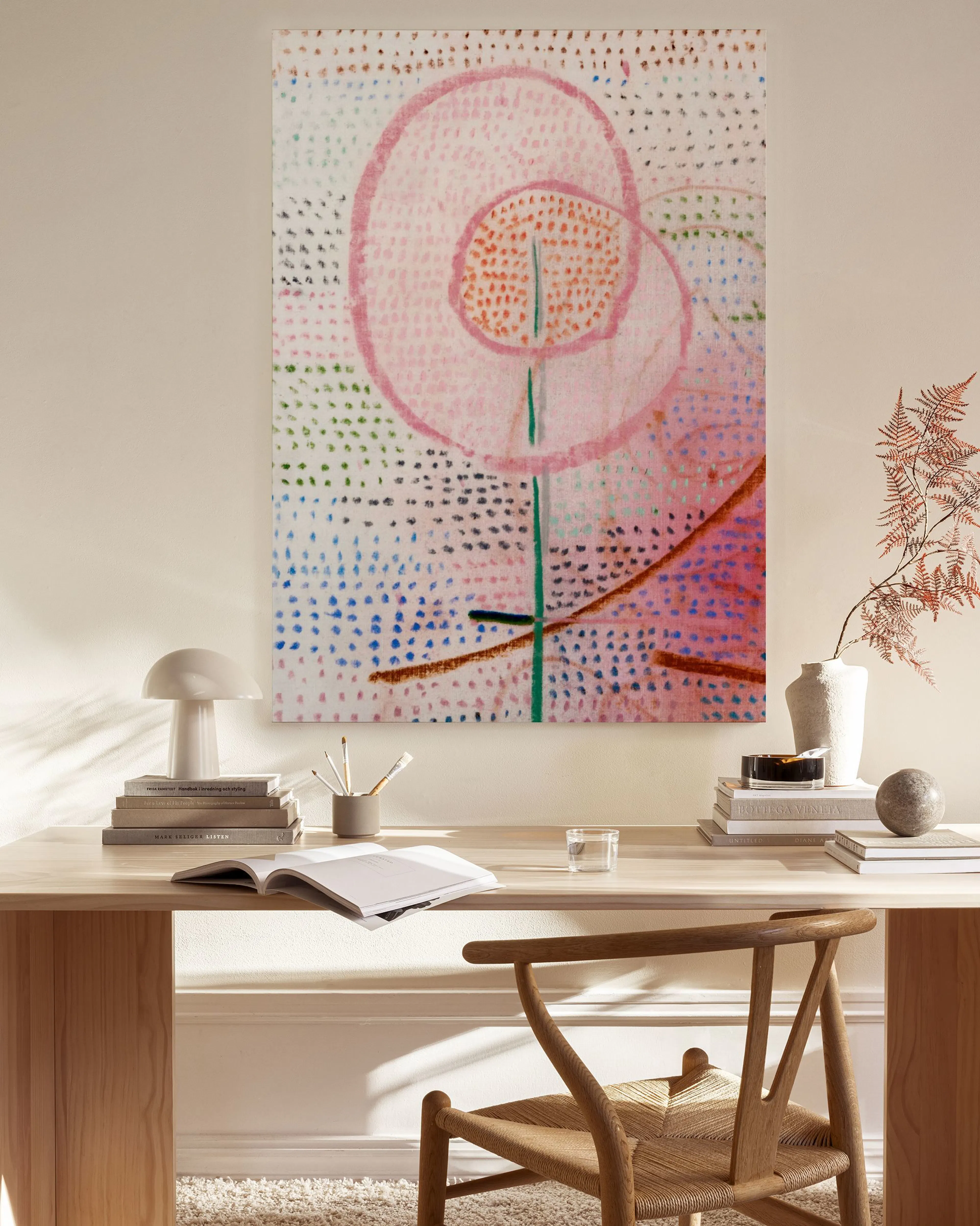 Leinwandbild mit abstrakter rosa Blüte auf gepunktetem Hintergrund, in einem hellen Wohnzimmer über einem Sideboard hängend.