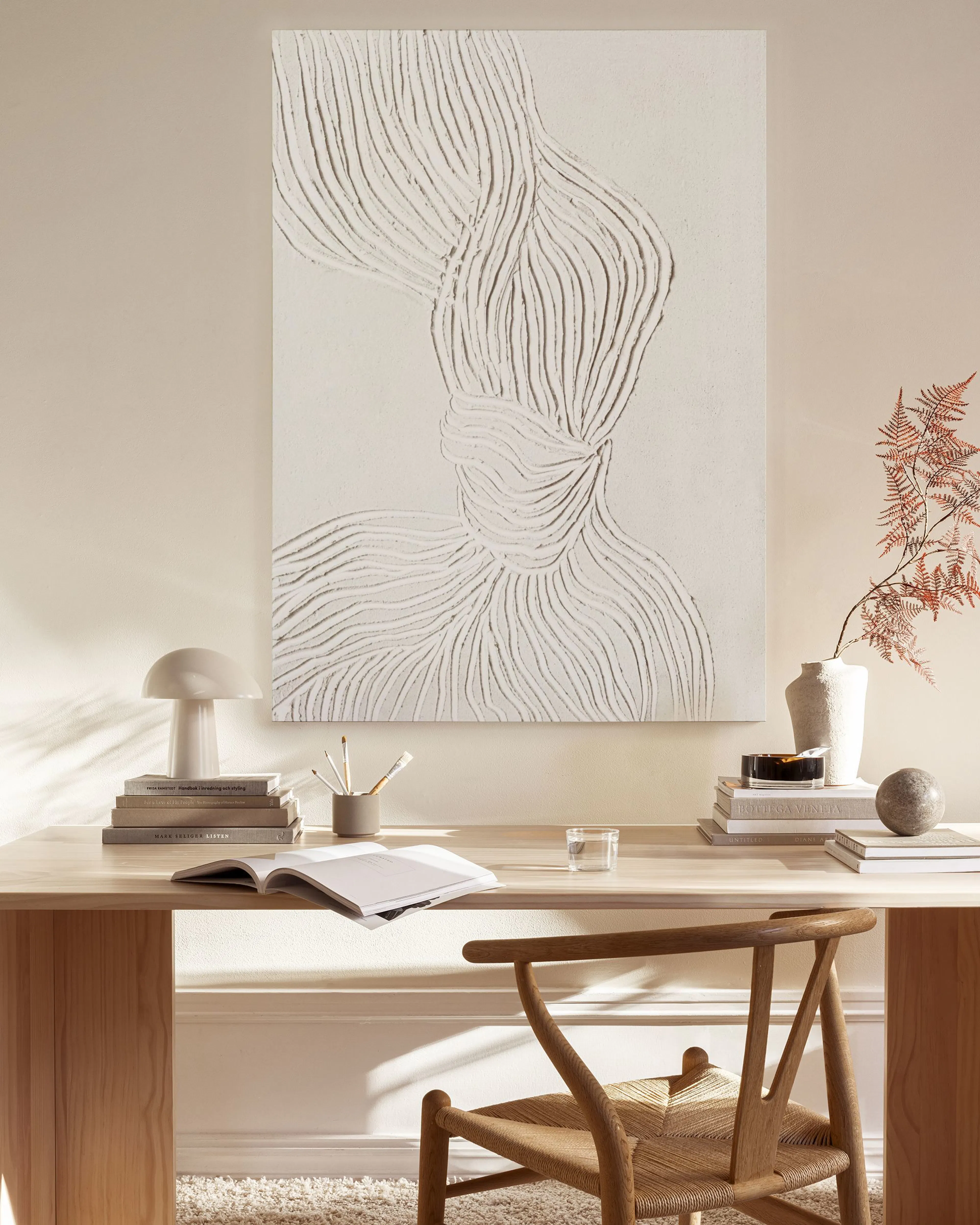 Ein Leinwandbild mit abstrakten, geschwungenen Linien in Weiß auf hellem Hintergrund, über einer Holzbank in einem Wohnzimmer.