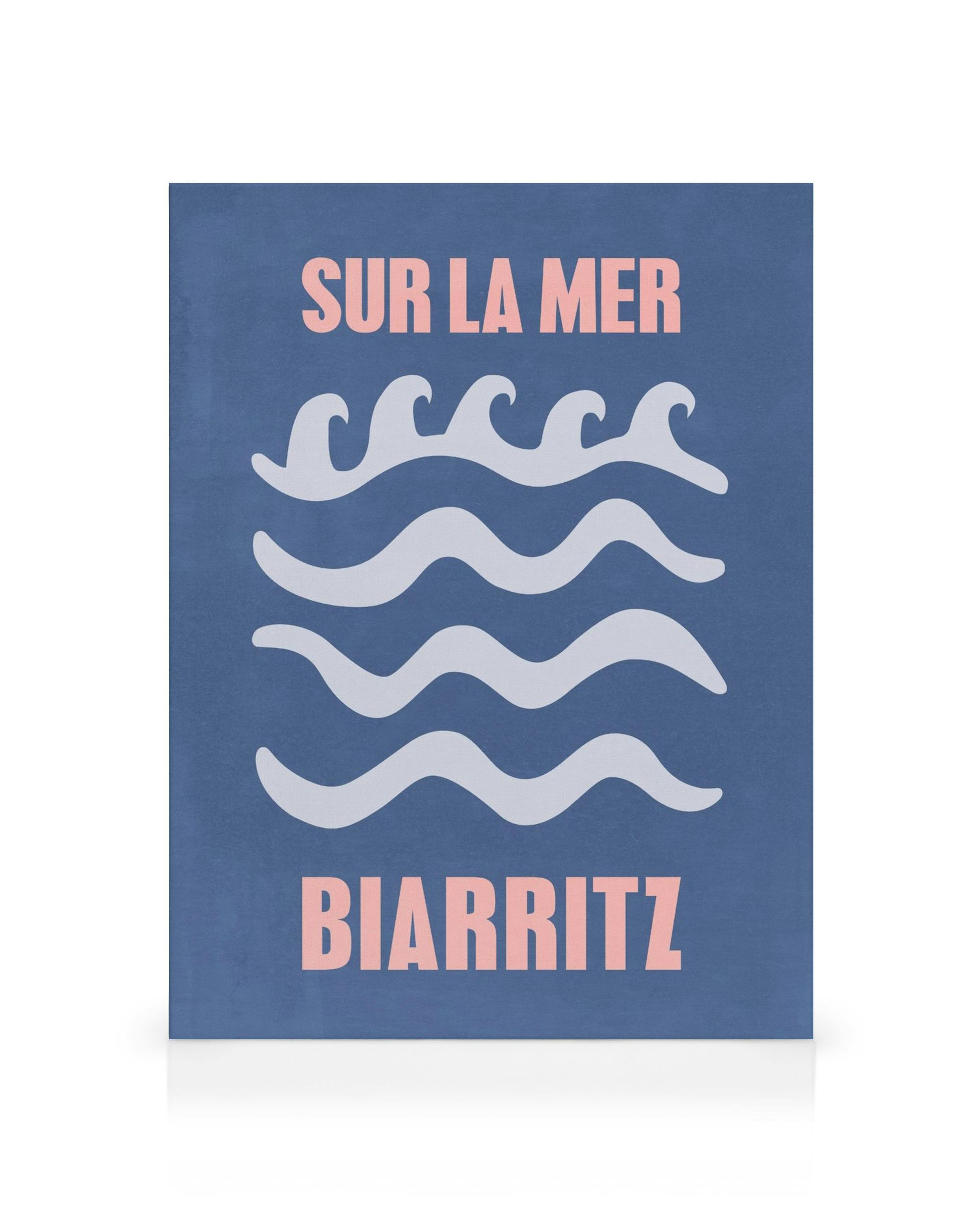 Grafisk canvastavla med vita vågiga linjer och rosa text Sur La Mer och Biarritz på blå bakgrund. Enkel väggkonst.