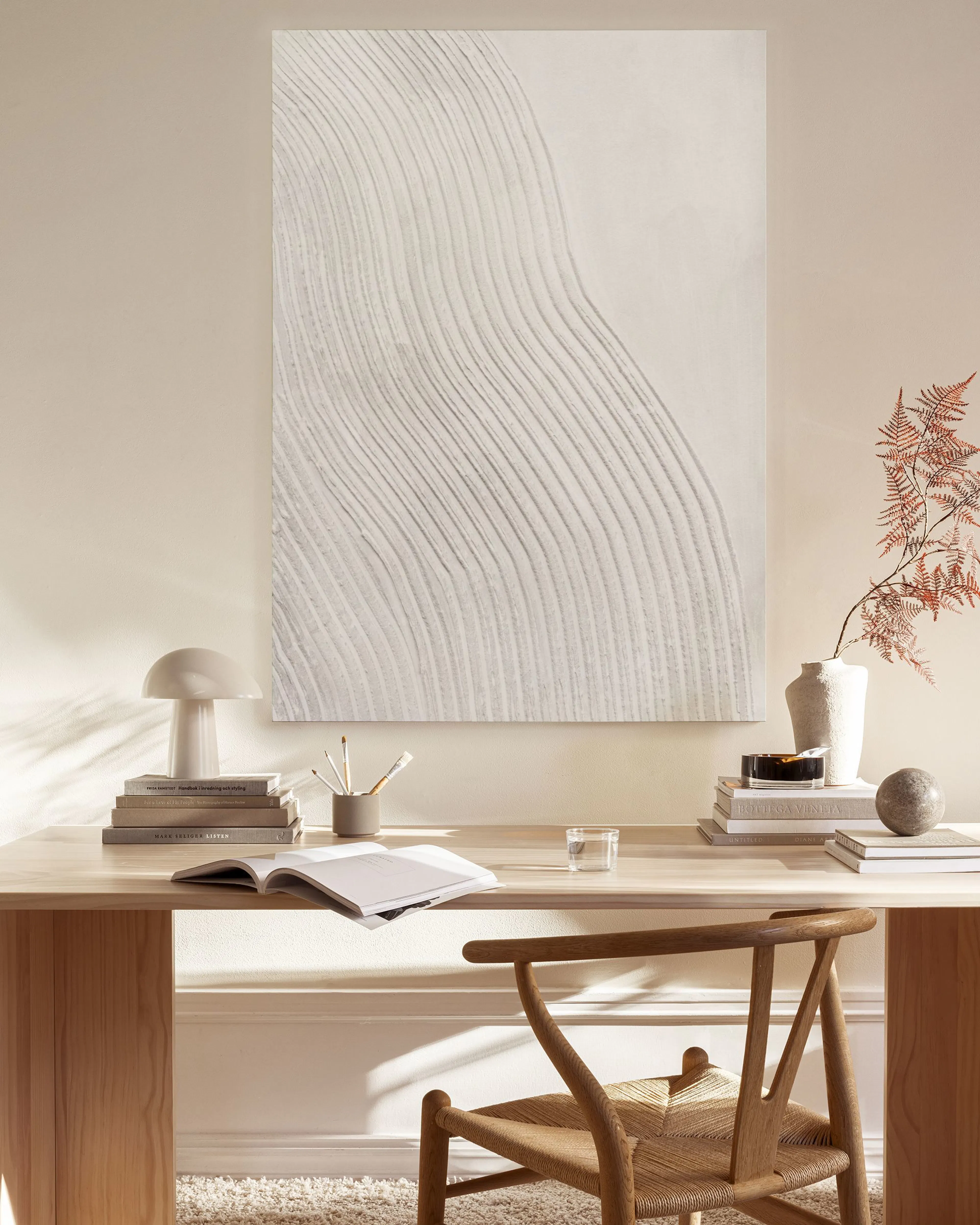 A canvas print with subtle white wavy lines on a beige background, hanging in a minimalist living room above a wooden console.