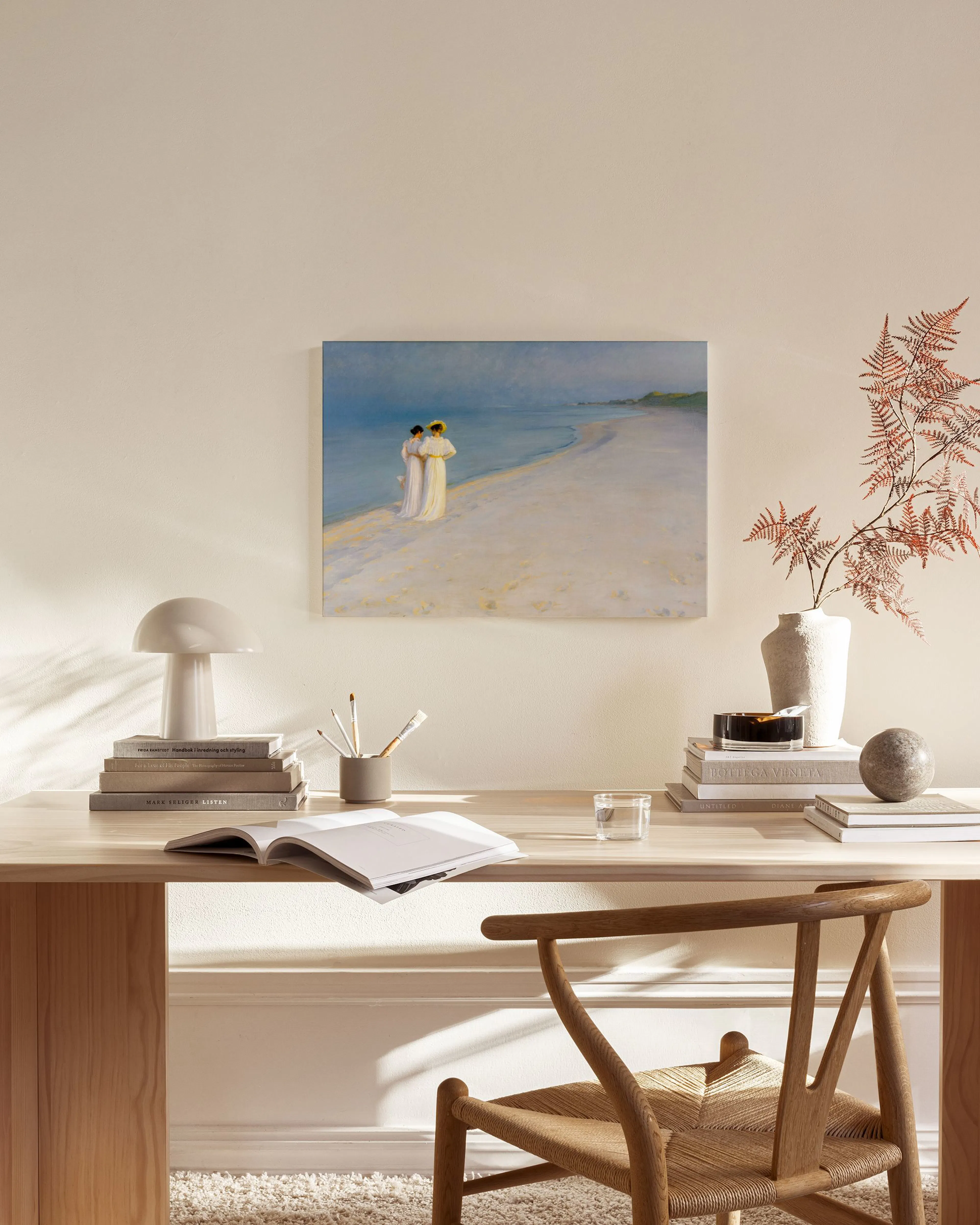 Leinwandbild mit zwei Frauen in hellen Kleidern am Strand, aufgehängt in einem modernen Wohnzimmer über einem Sideboard.