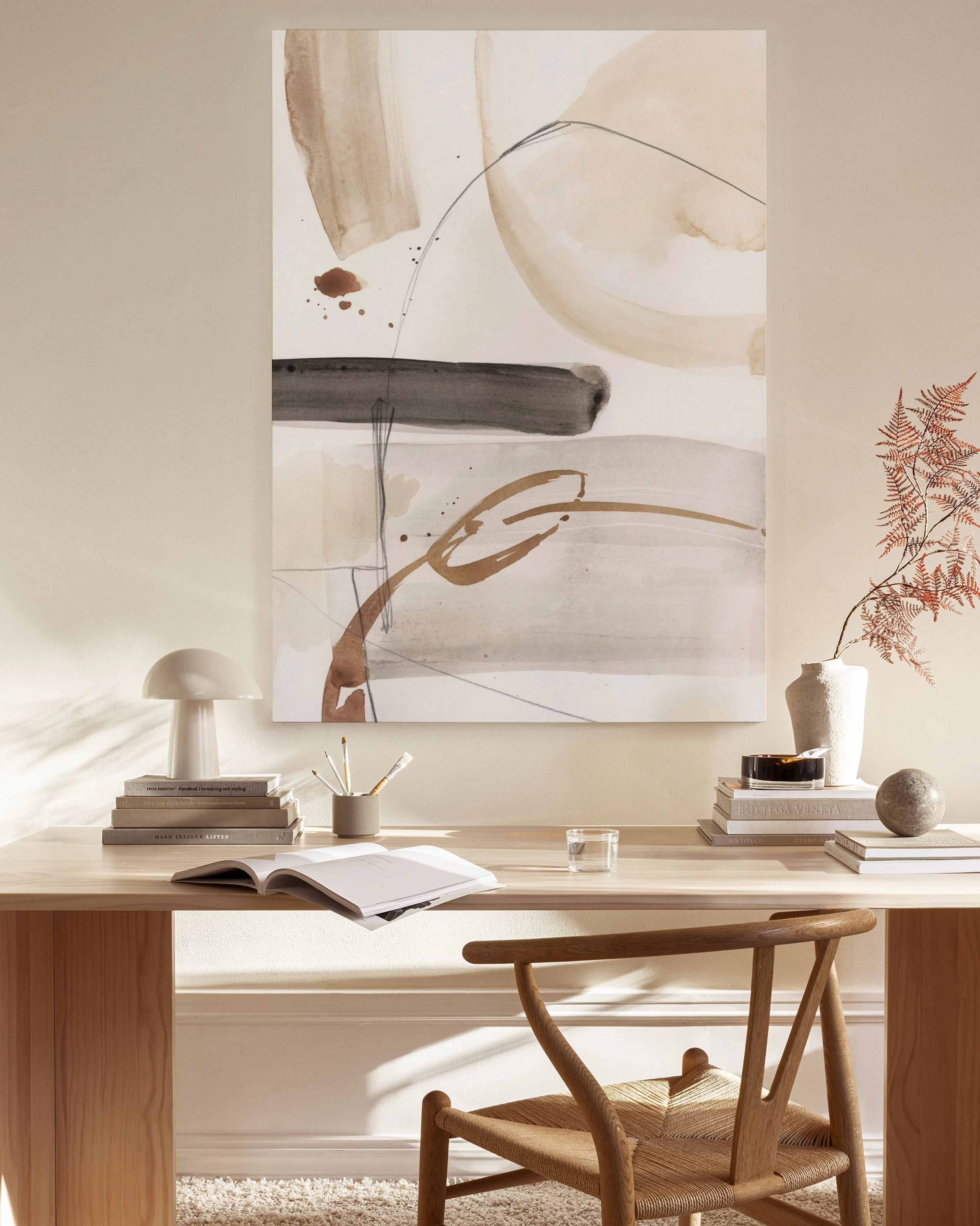 Stampa su tela con forme astratte nei toni del marrone e beige, esposta in un salotto moderno.