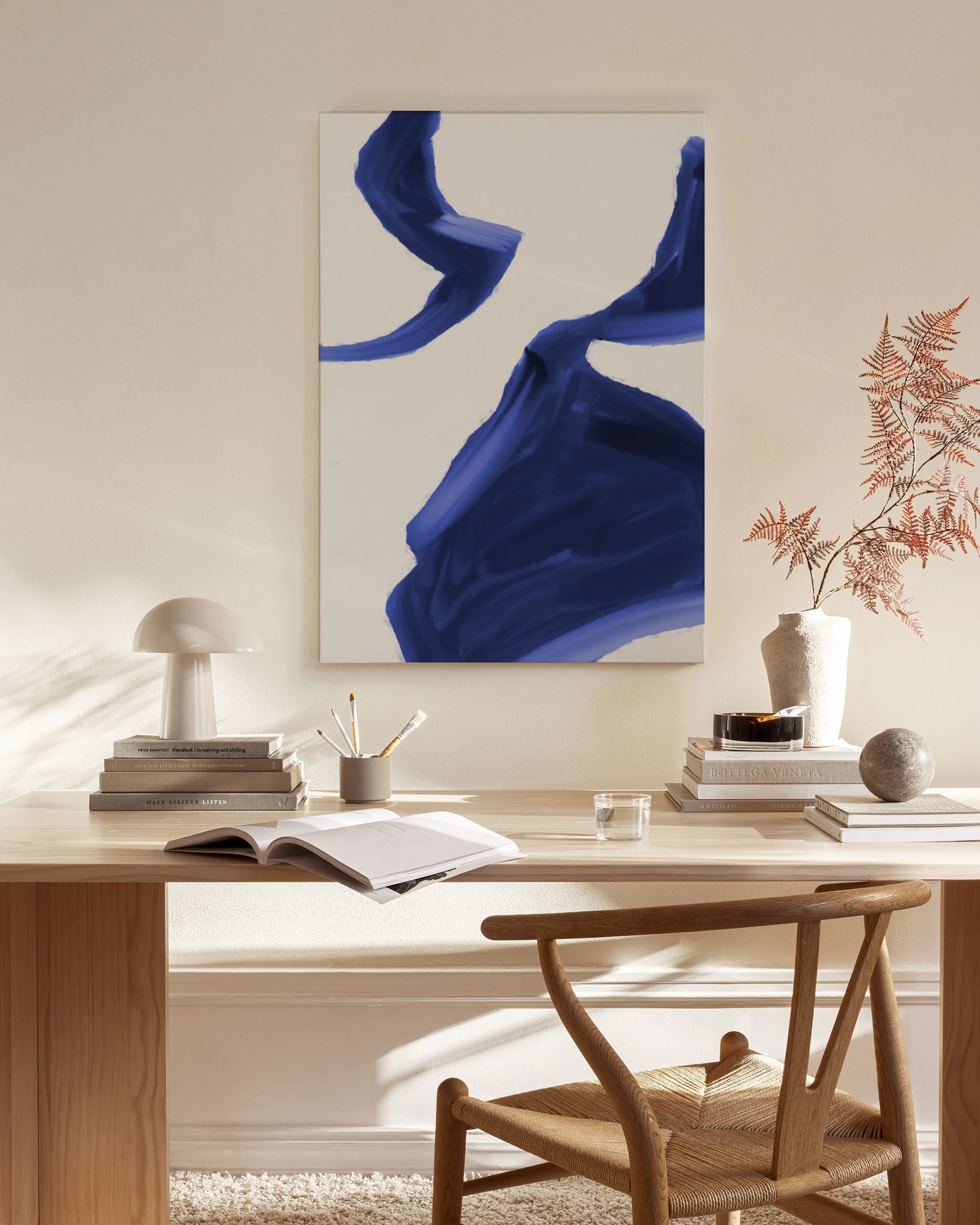 Canvas met blauwe, abstracte penseelstreken op een witte achtergrond, hangend boven een houten dressoir in een woonkamer.