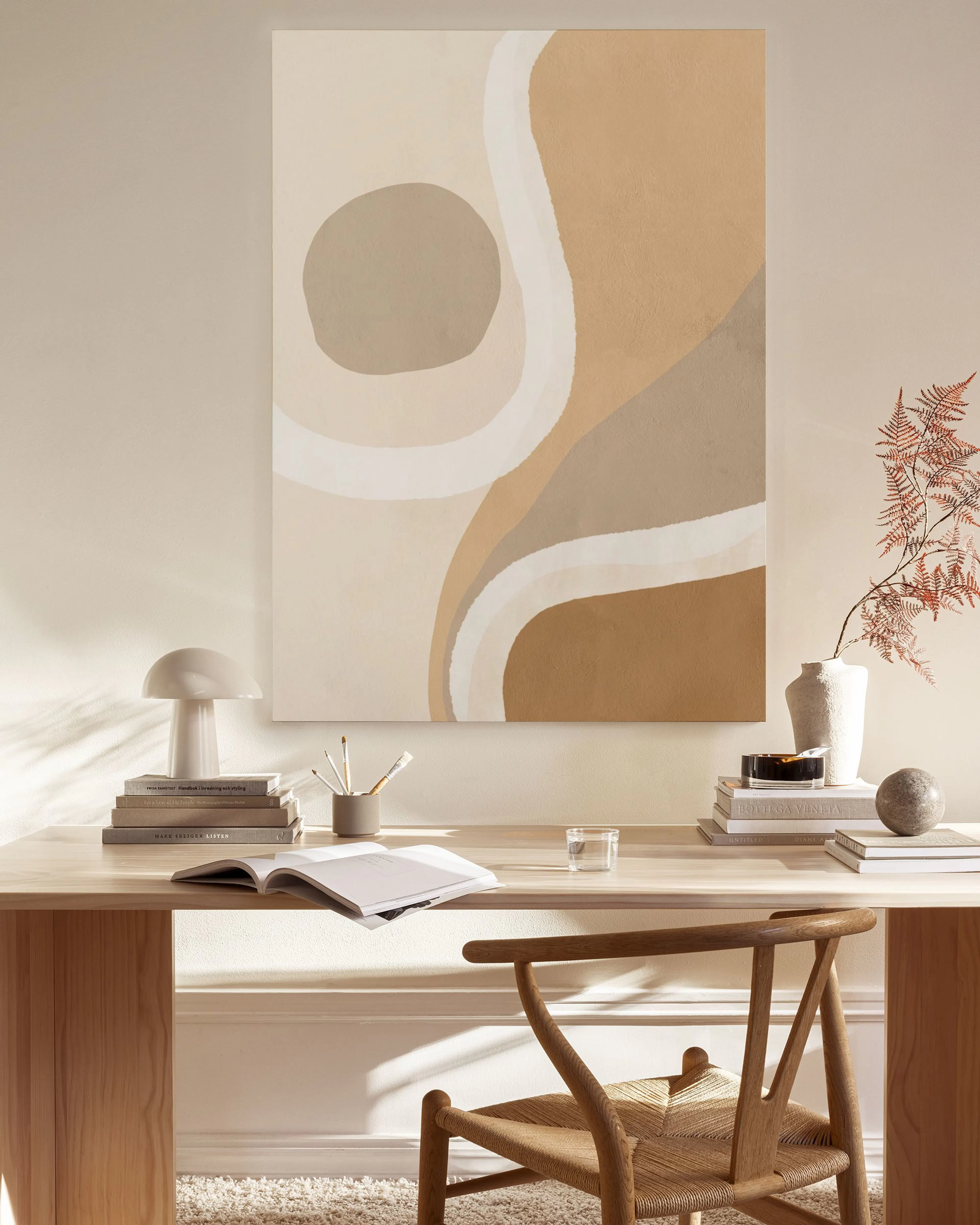 Lienzo con formas orgánicas en tonos beige, marrón y blanco, colgado en una sala de estar moderna.