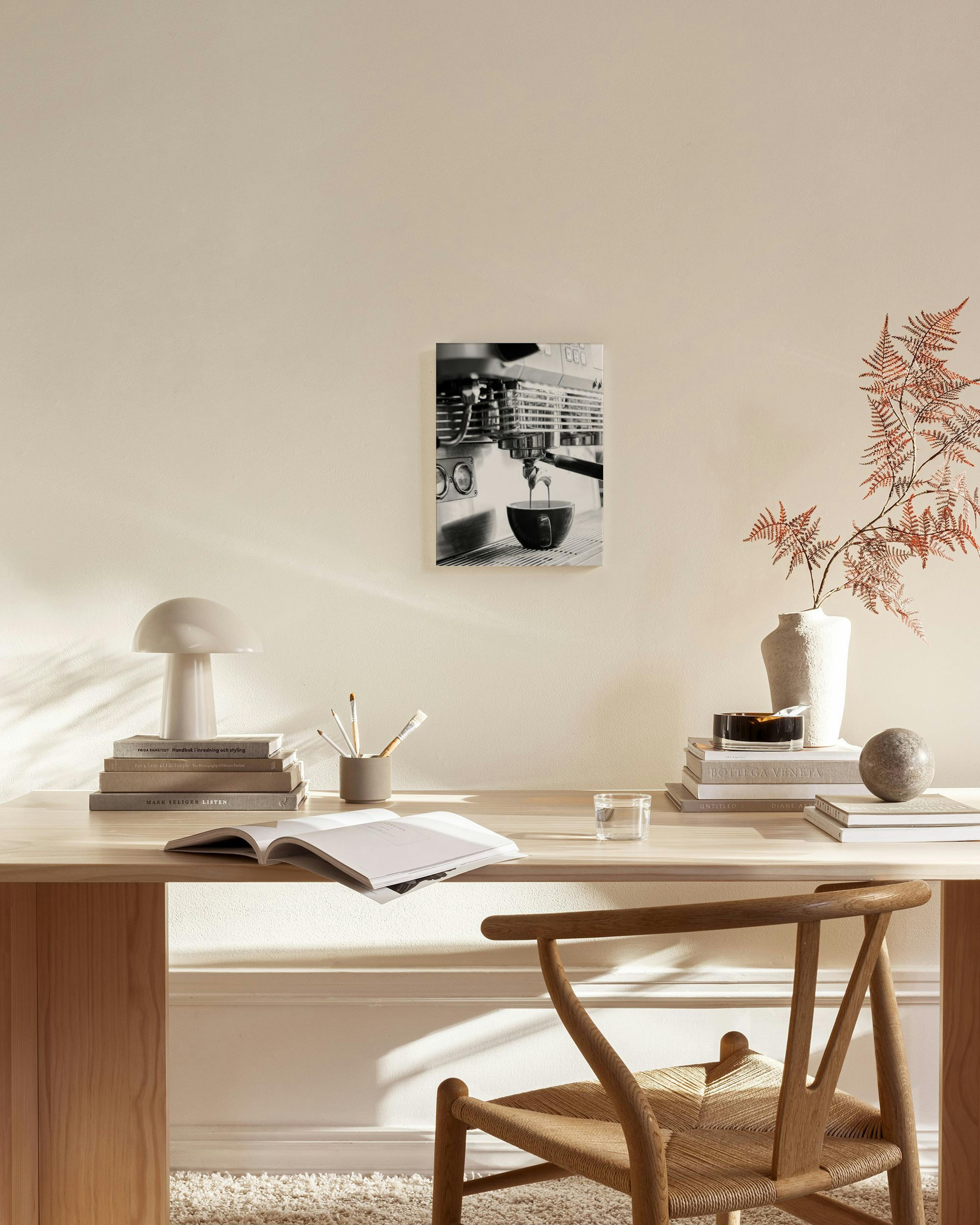 Lienzo monocromático de una máquina de café expreso vertiendo café en una taza, colgado en una sala de estar moderna.