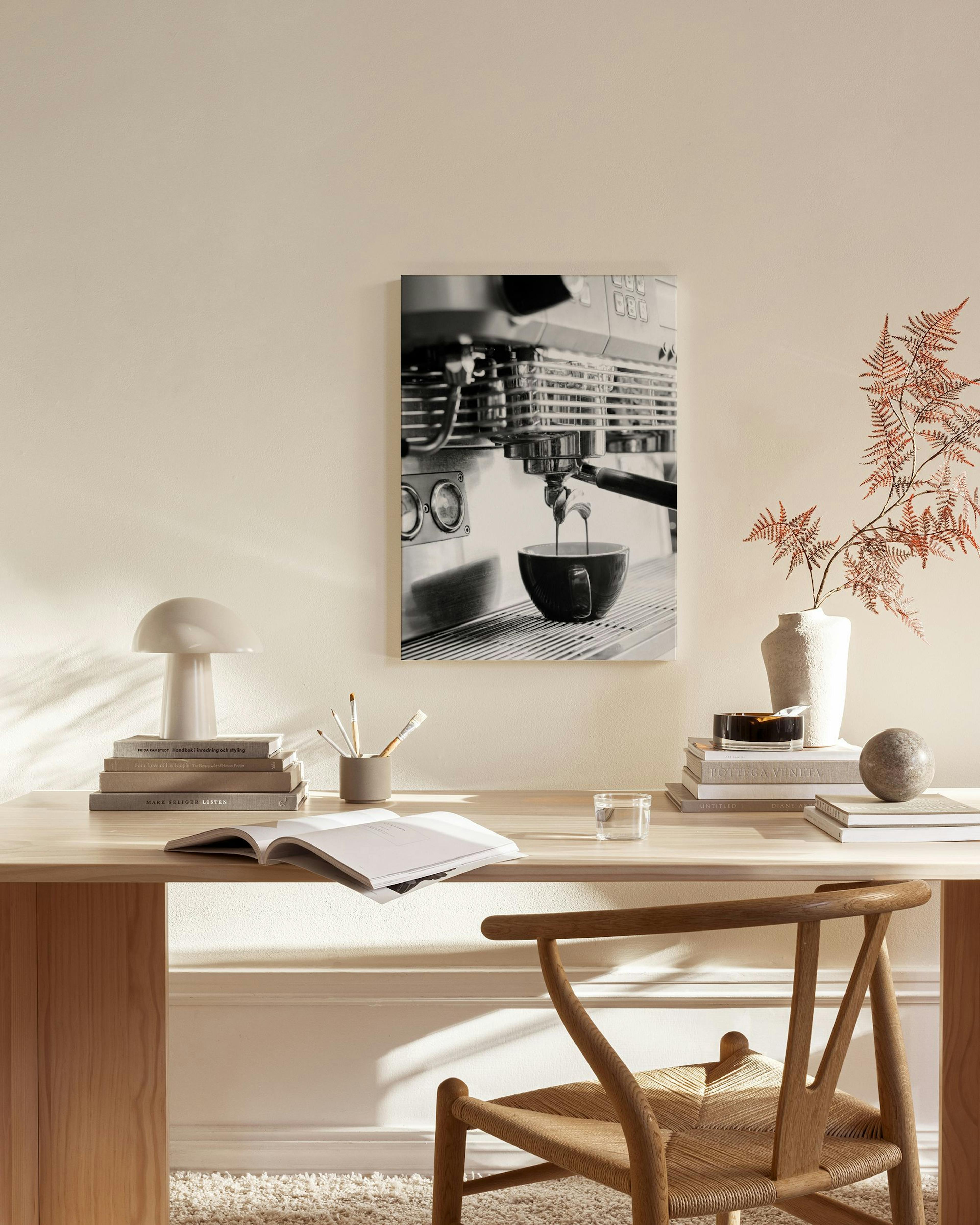 Stampa su tela in bianco e nero di una macchina da caffè che eroga in una tazza, appesa in un soggiorno moderno.