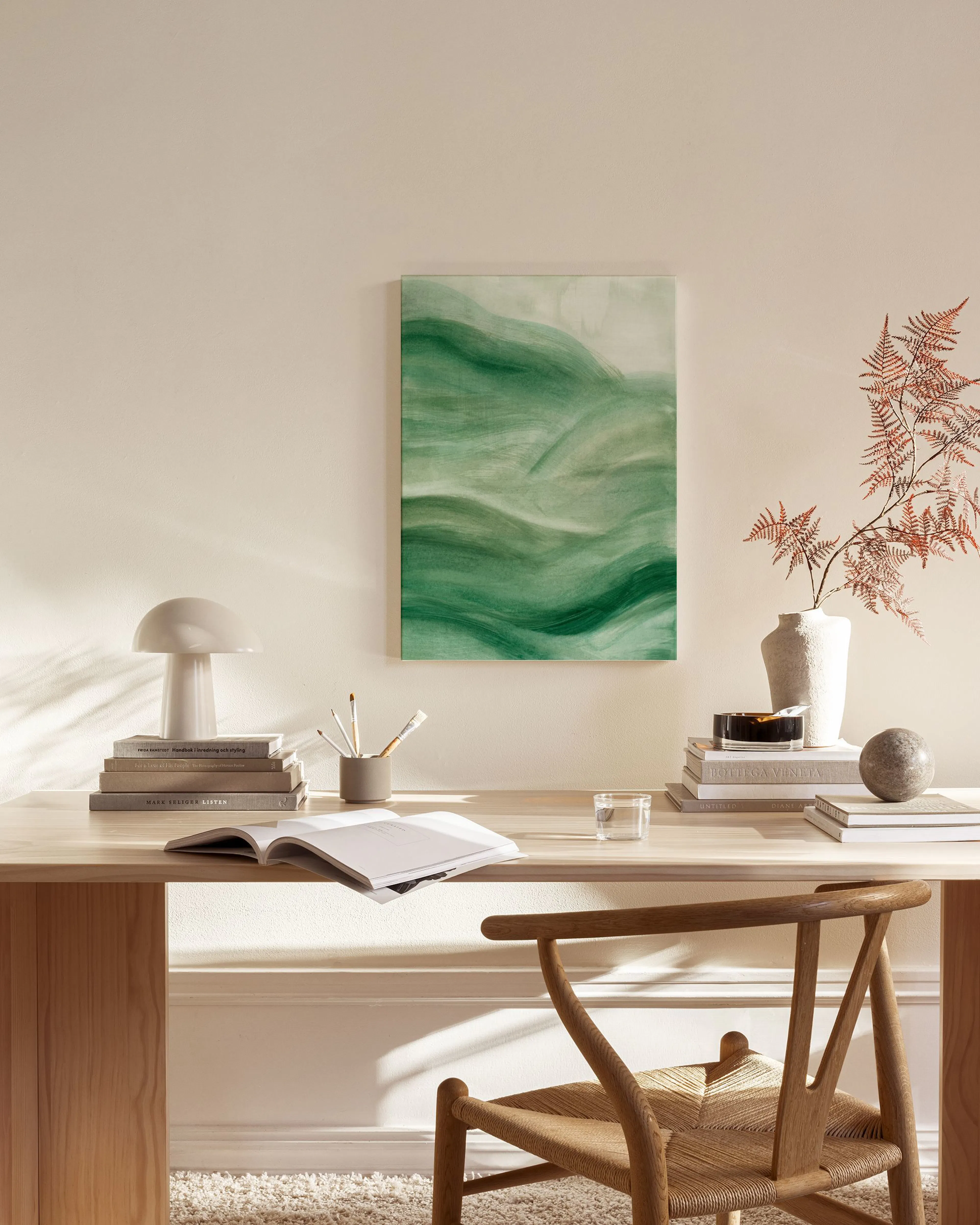 Lienzo con ondas verdes y blancas sobre fondo claro, colgado en una sala de estar moderna sobre un mueble de madera.