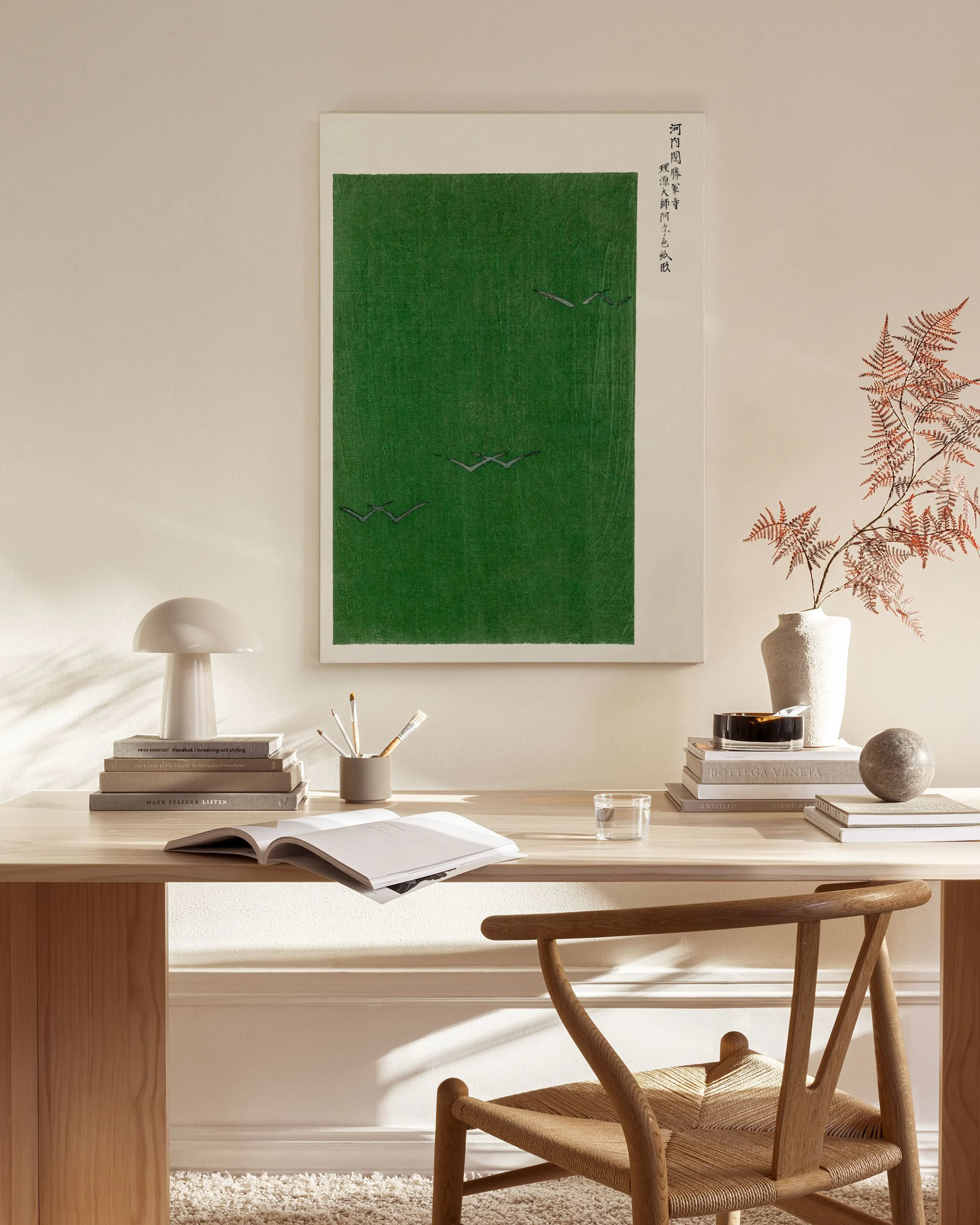 Toile verte avec des grues volantes et texte japonais, accrochée dans un salon scandinave épuré.