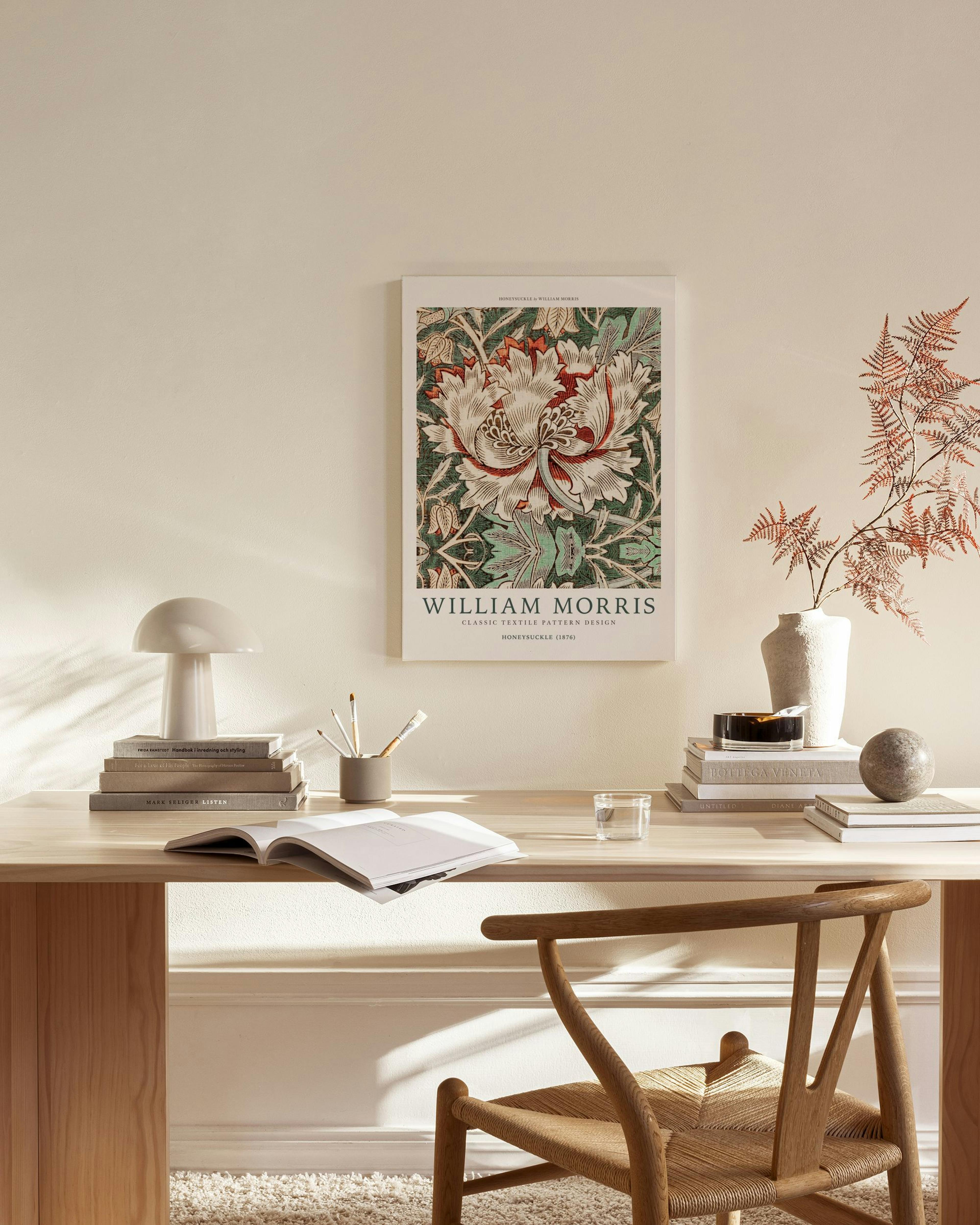 A William Morris canvas print with white and red honeysuckle flowers on a green leafy background, hanging in a modern living roo