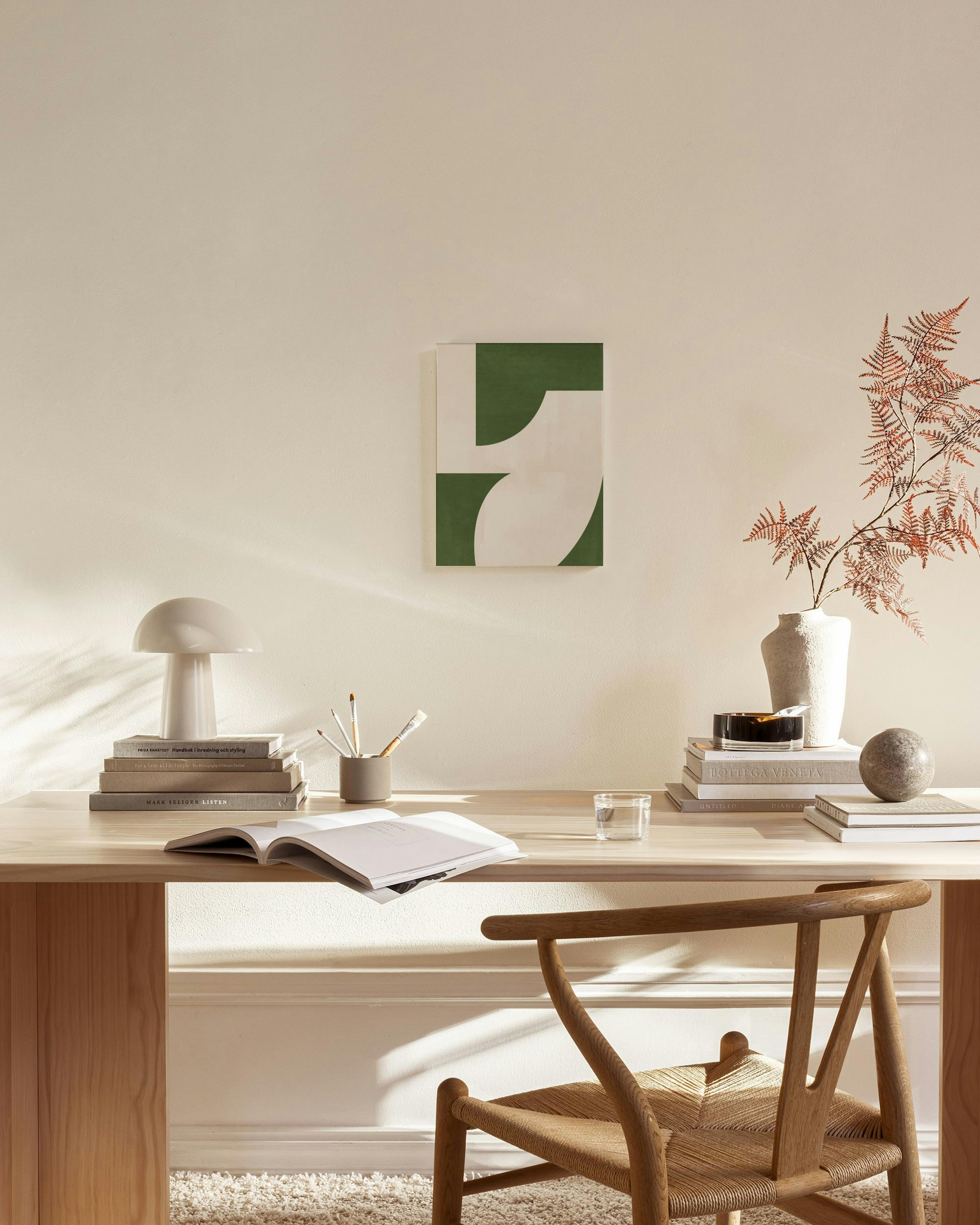 Canvas met abstracte vormen in donkergroen en beige, hangend in een minimalistische woonkamer.