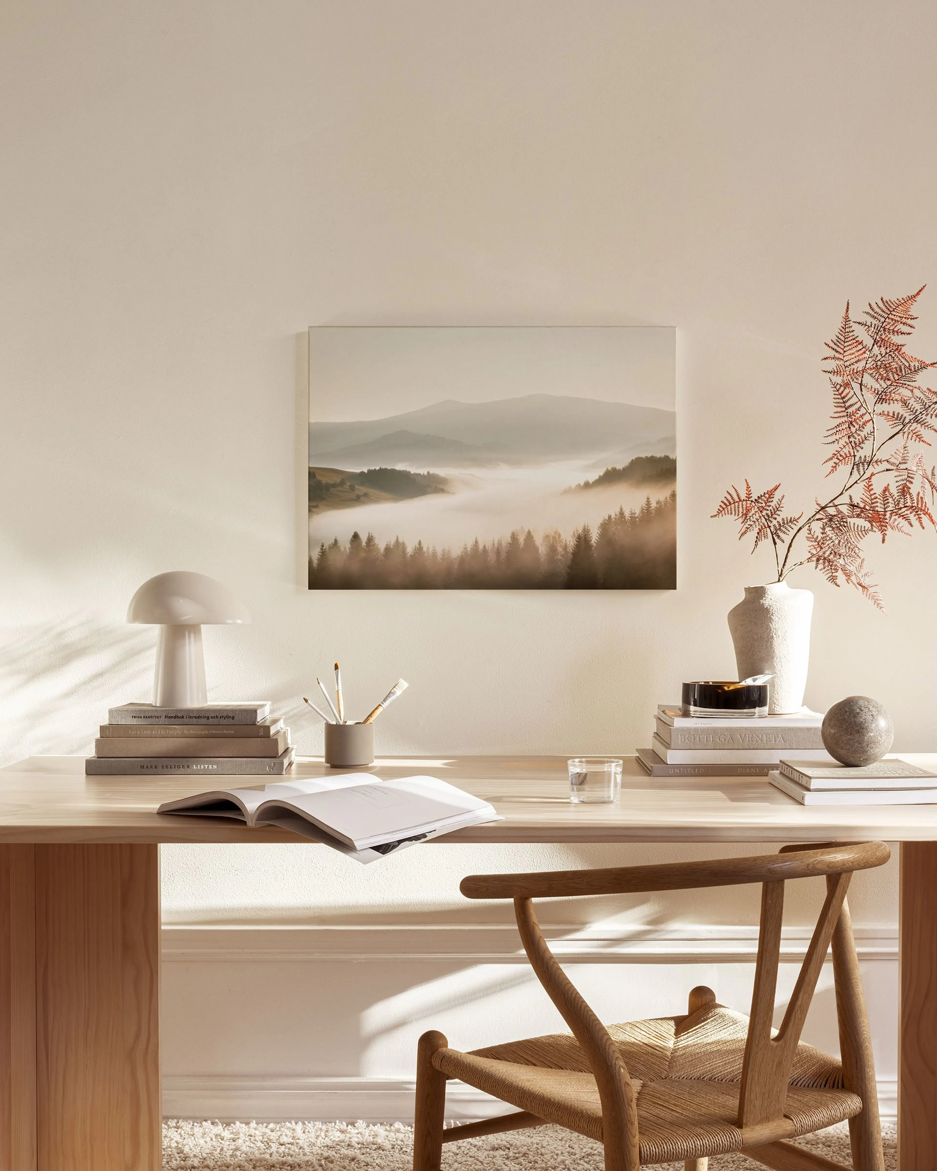 Canvas met mistig boslandschap en bergen, hangend in een neutrale woonkamer boven een houten dressoir.
