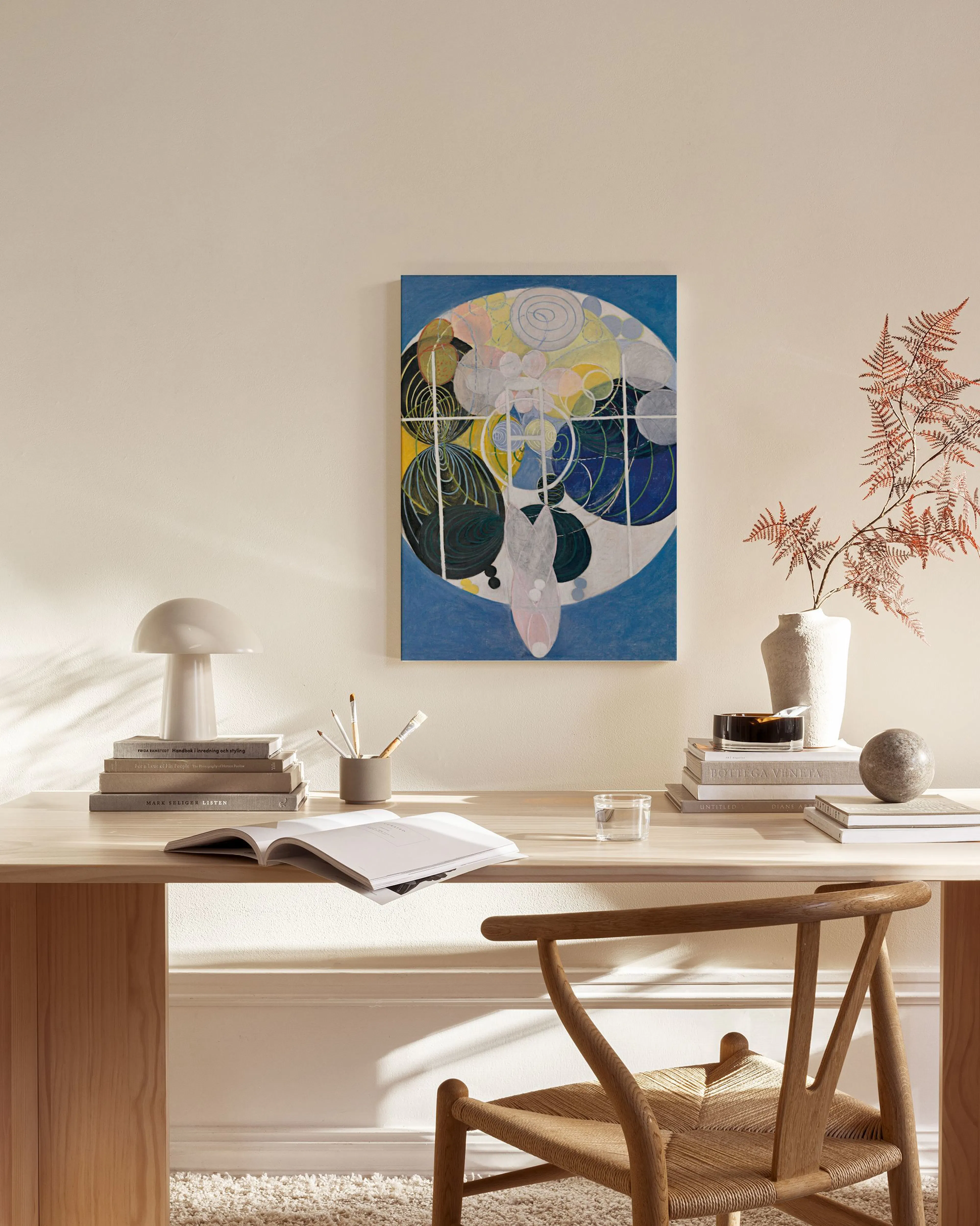 Lienzo abstracto con formas orgánicas en tonos azules, amarillos y negros, colgando en una sala de estar moderna sobre un mueble