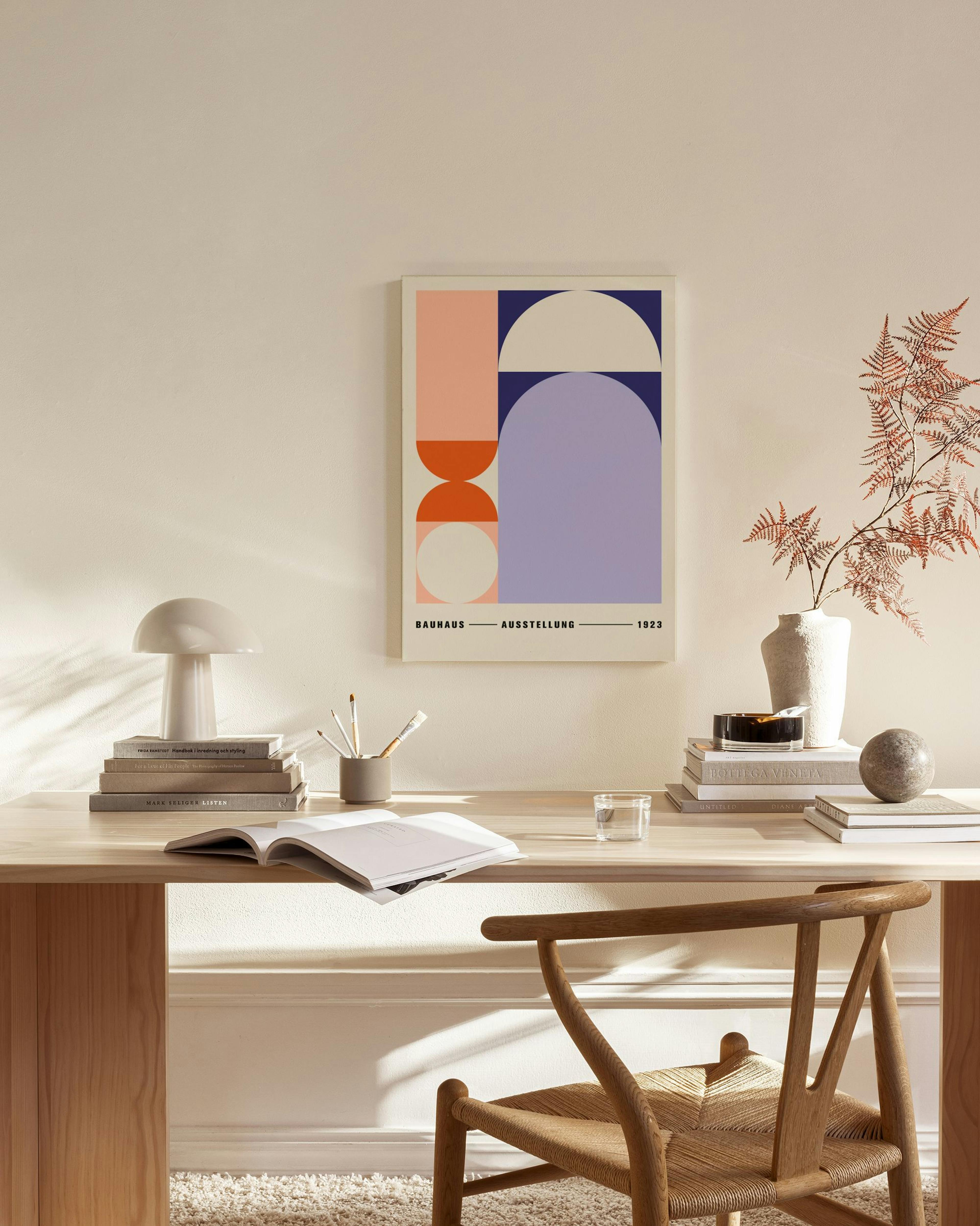 Lienzo Bauhaus con formas geométricas rosa, naranja, morado y beige, colgando en una sala de estar minimalista.