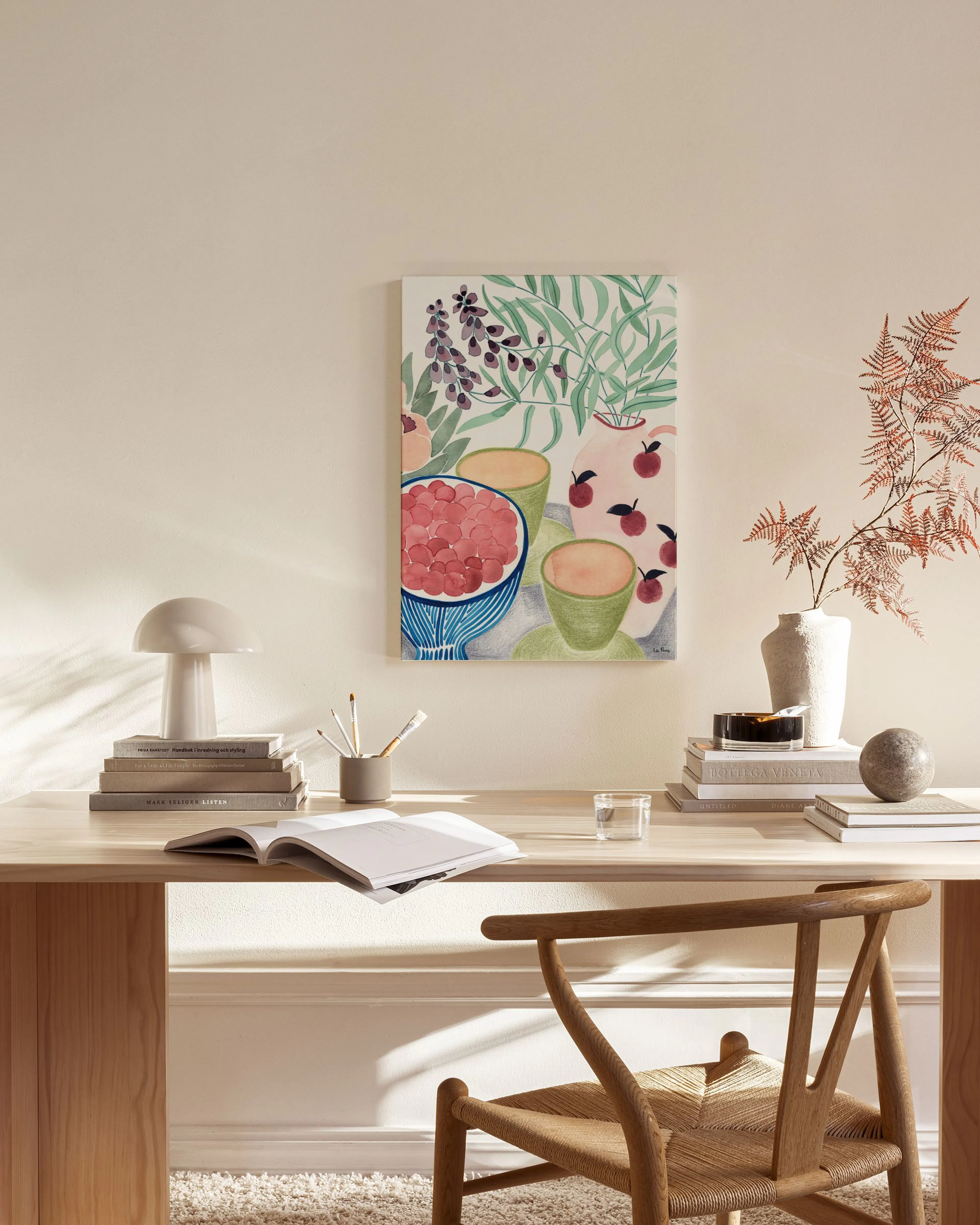 A vibrant still life print featuring a bowl of red berries, green cups, and a pitcher with red apples, hanging in a modern livin