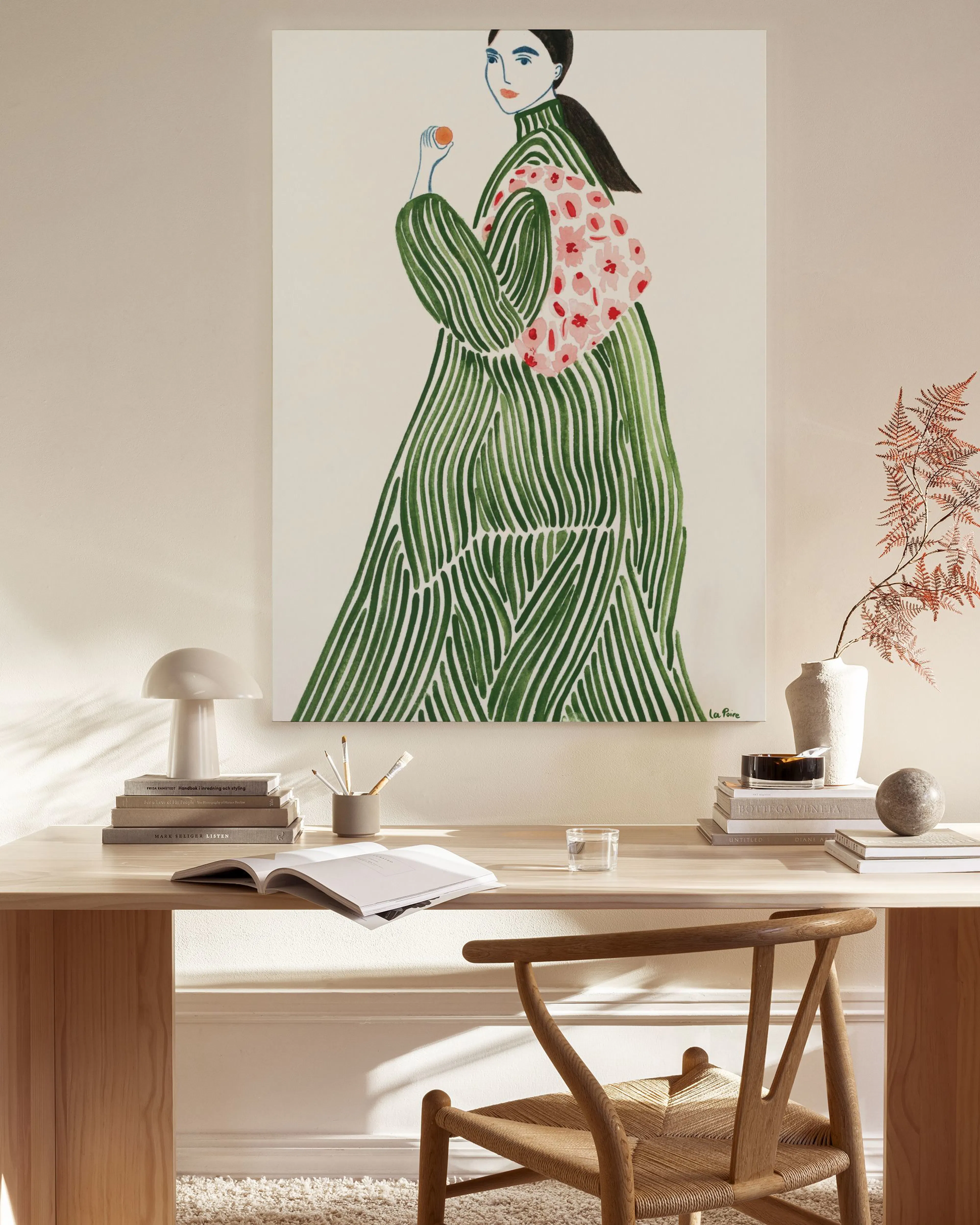 A canvas print of a woman in a green striped dress with a floral shawl, hanging in a light-filled living room above a wooden con
