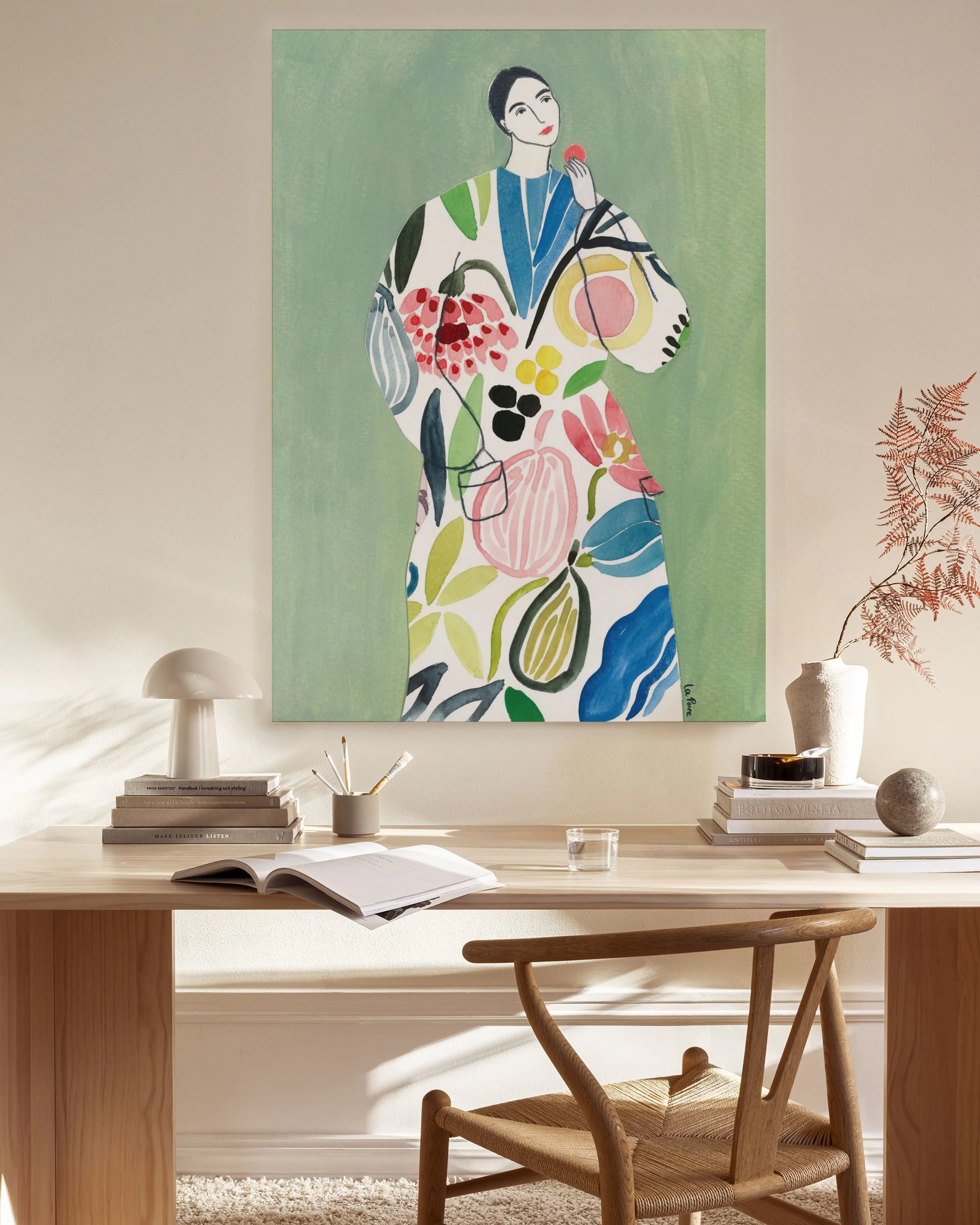 A colourful canvas print of a woman in a floral patterned dress, hanging in a light-filled living room above a wooden console ta