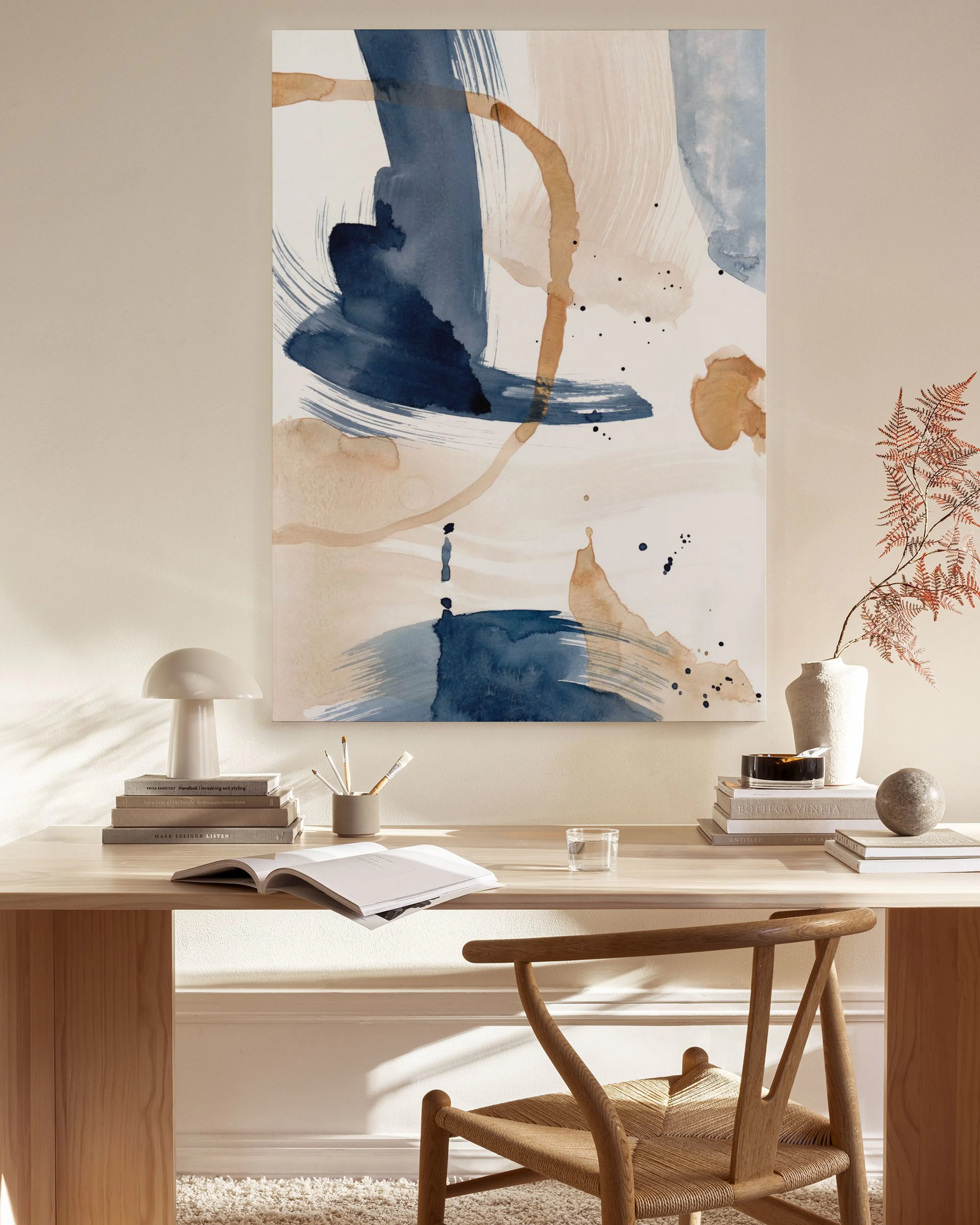 Canvas met blauw en beige organische vormen, spatten en lijnen, hangend boven een houten dressoir in een woonkamer.