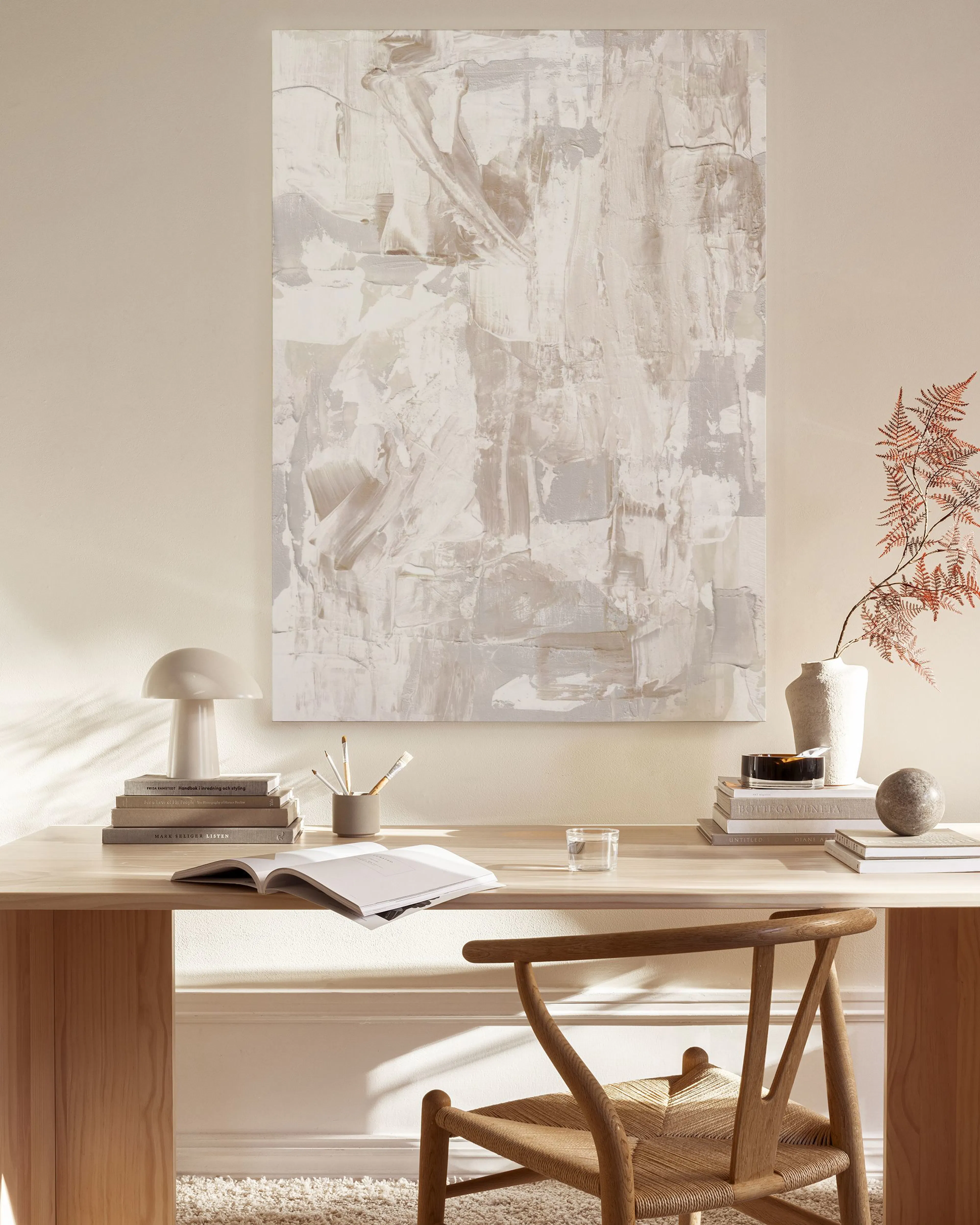 Toile abstraite beige et blanc cassé aux textures apparentes, accrochée au-dessus dun meuble bas dans un salon moderne.