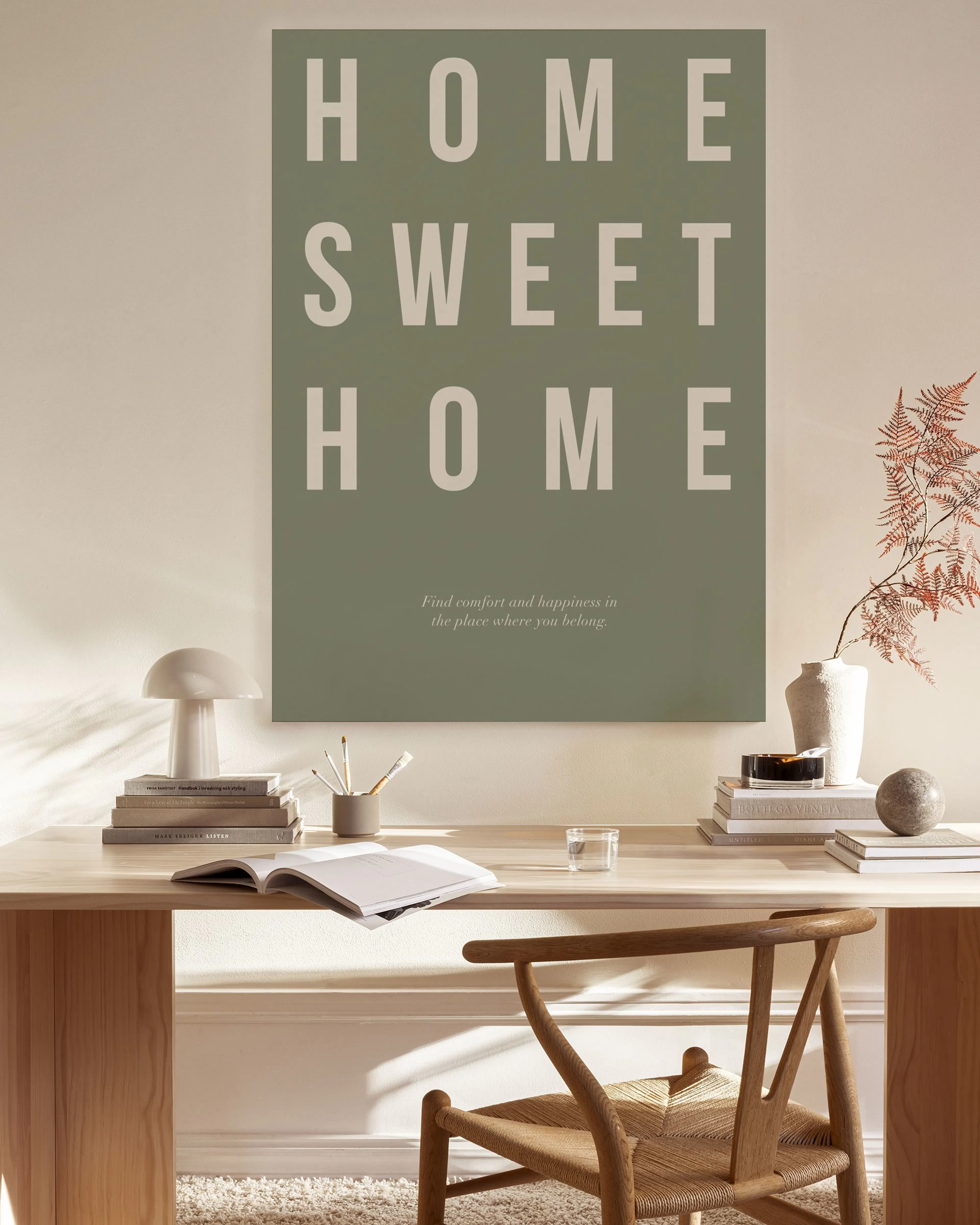 A canvas print with the phrase HOME SWEET HOME in light beige letters on a sage green background, with a small quote below.