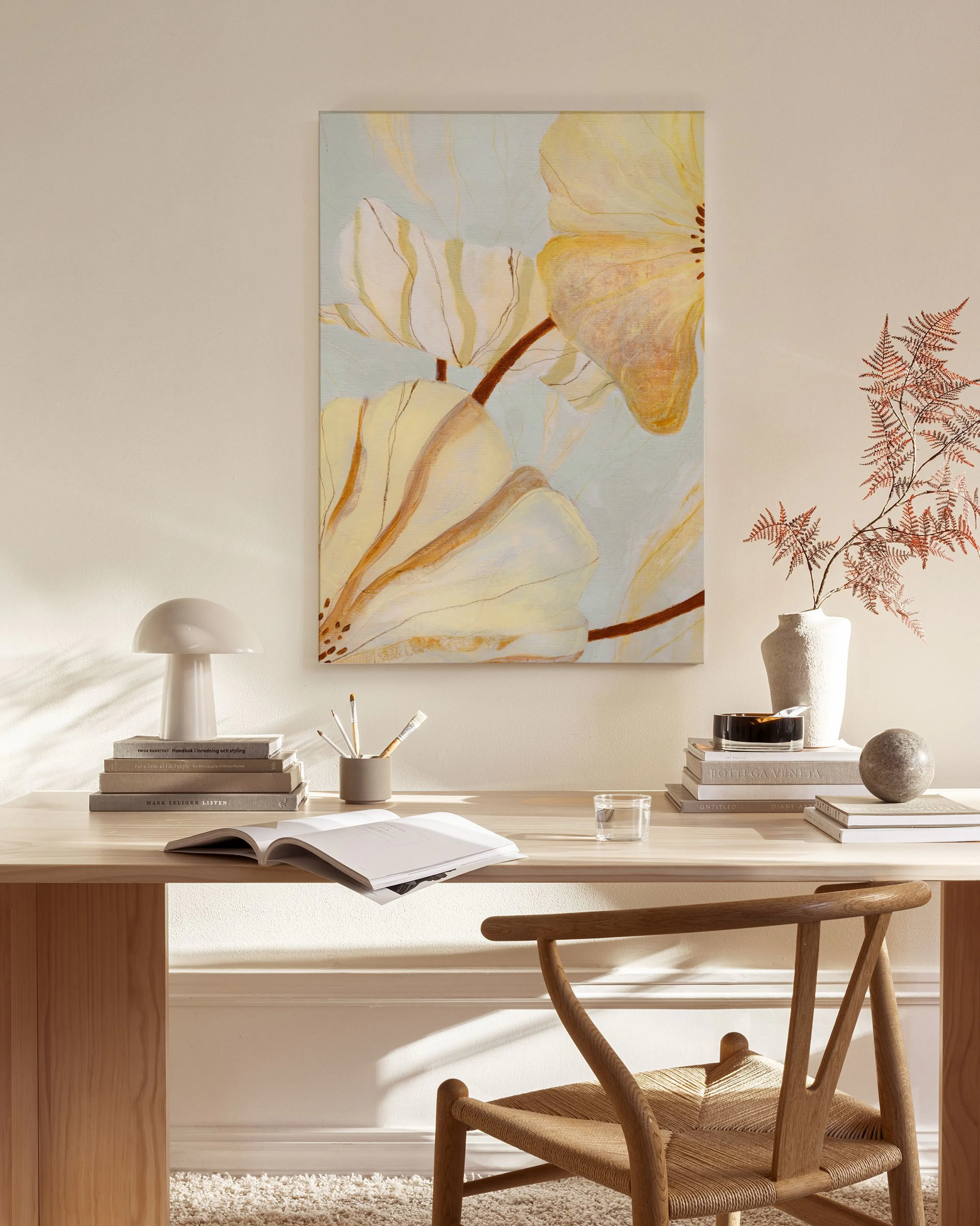Canvas print of abstract yellow flowers on a light blue background, hanging in a bright, minimalist living room.