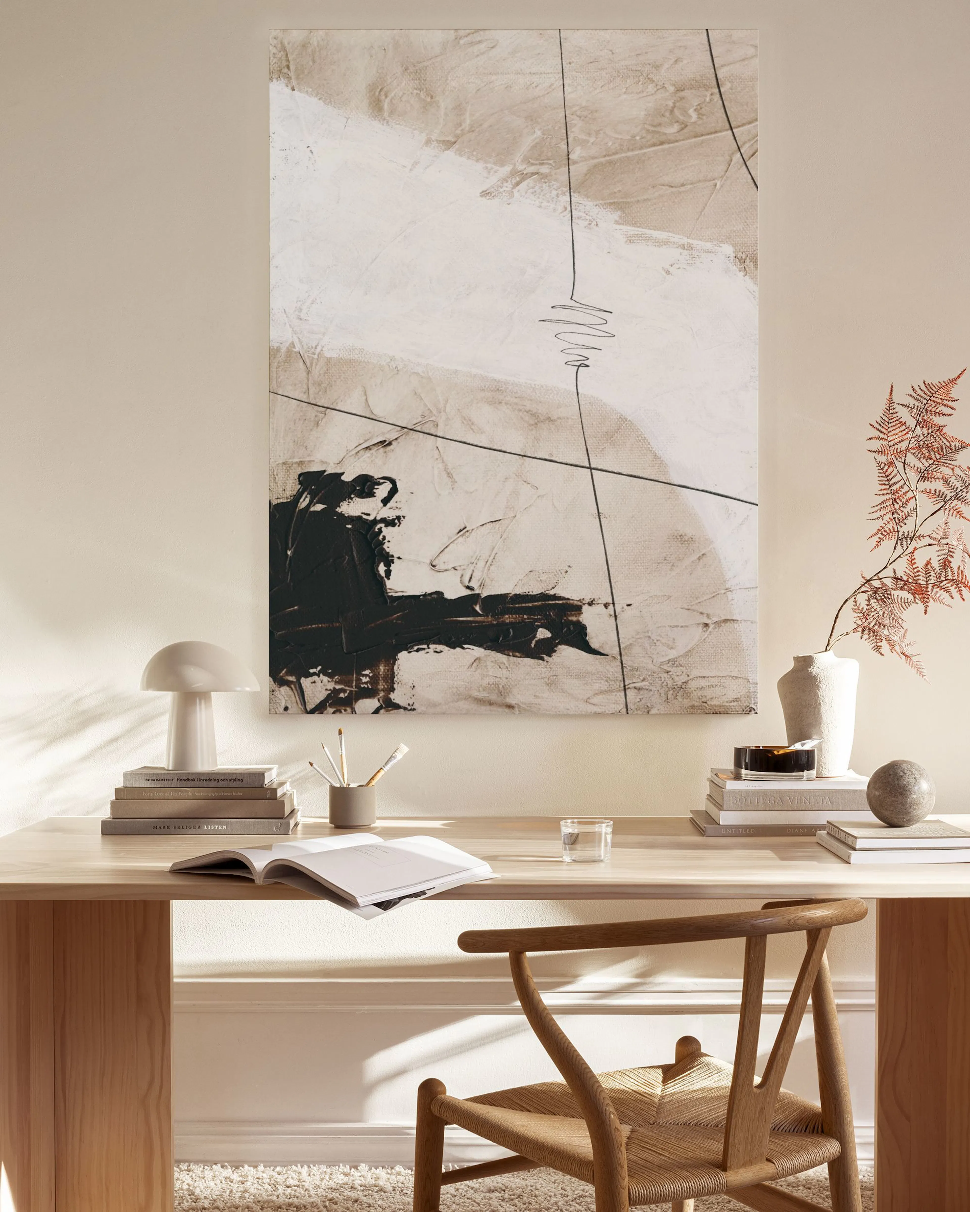 Lienzo abstracto con formas orgánicas en tonos beige, blanco y negro, y líneas finas, colgado en una sala moderna.