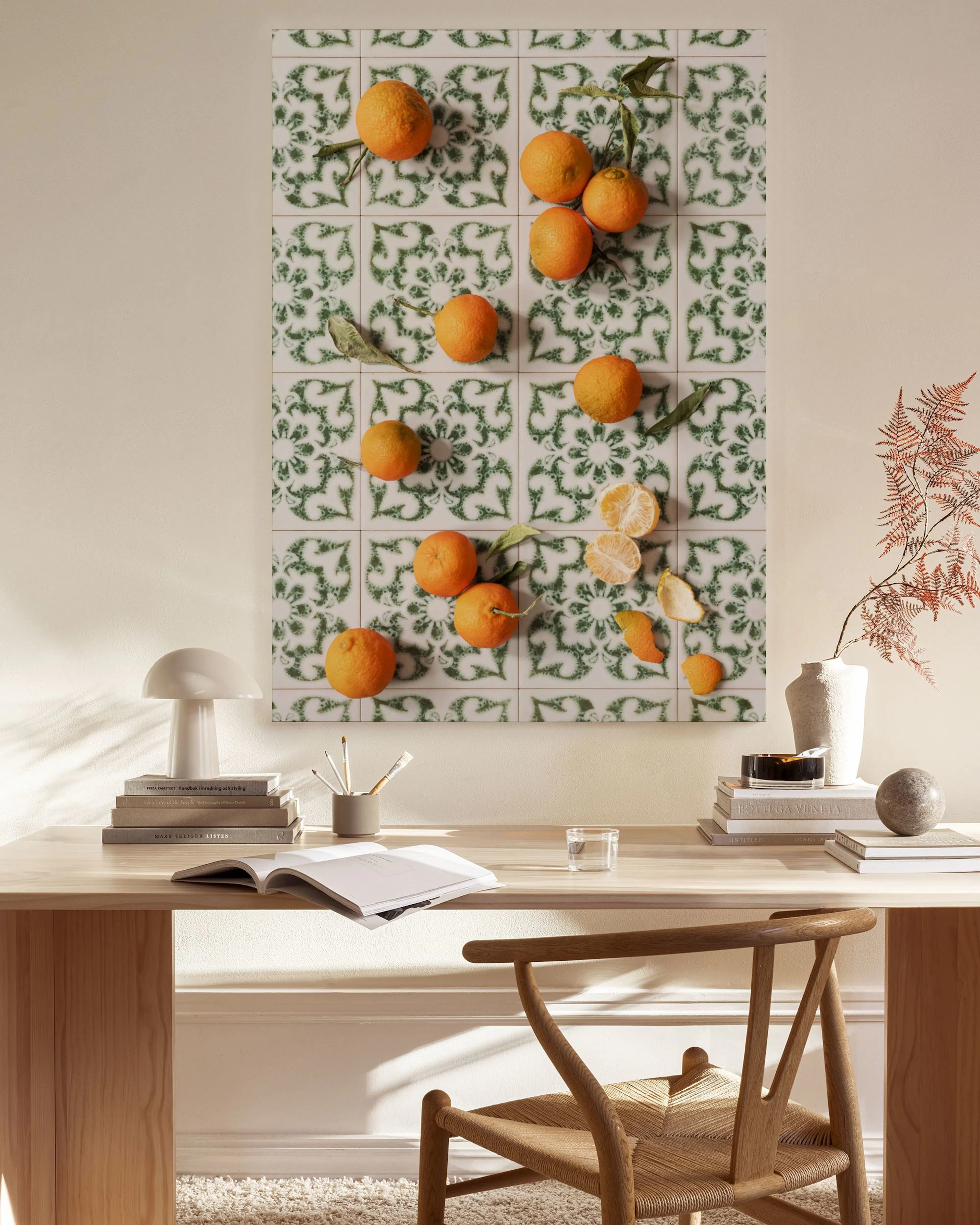Tela decorativa com laranjas sobre azulejos portugueses em verde e branco, exibida numa sala de estar com mobiliário de madeira 