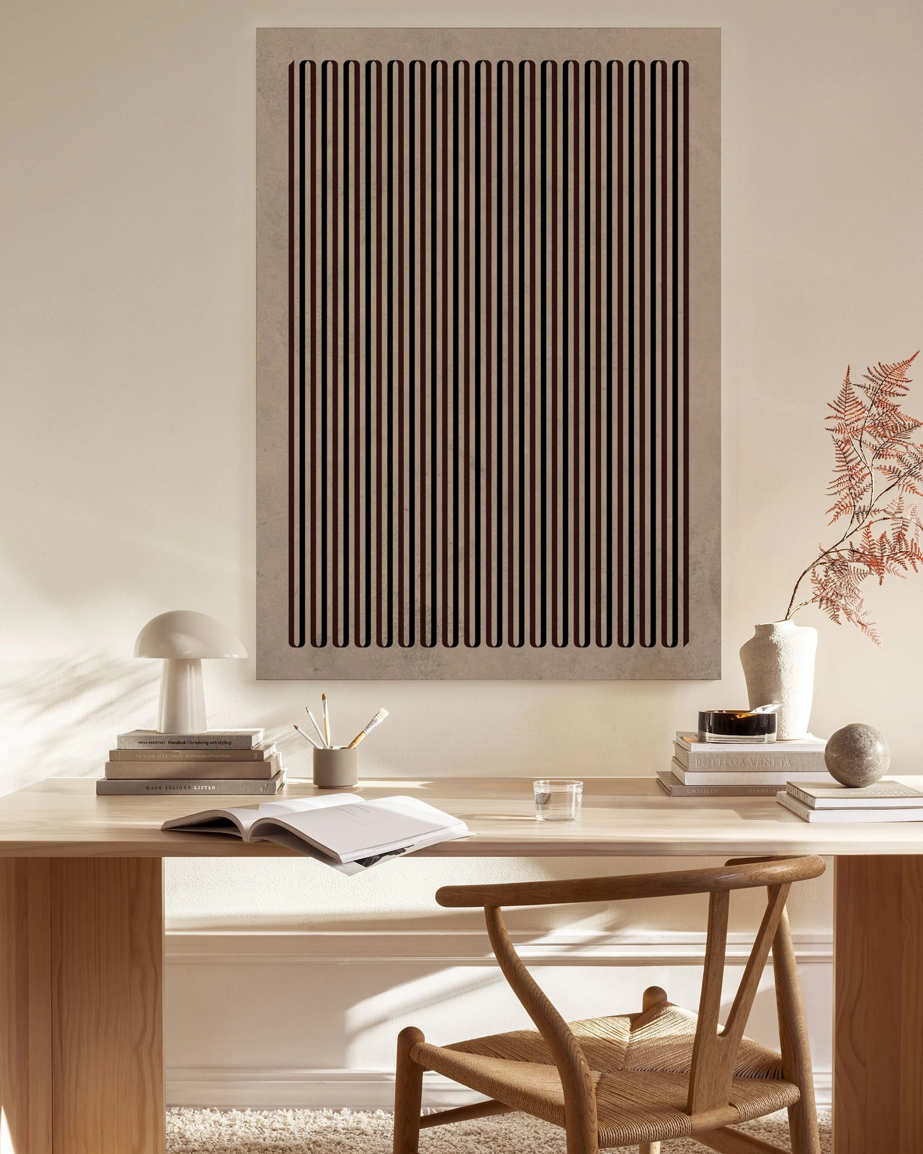 Tela decorativa com padrão de linhas verticais em tons de rosa e preto sobre fundo bege, exibida numa sala de estar minimalista.