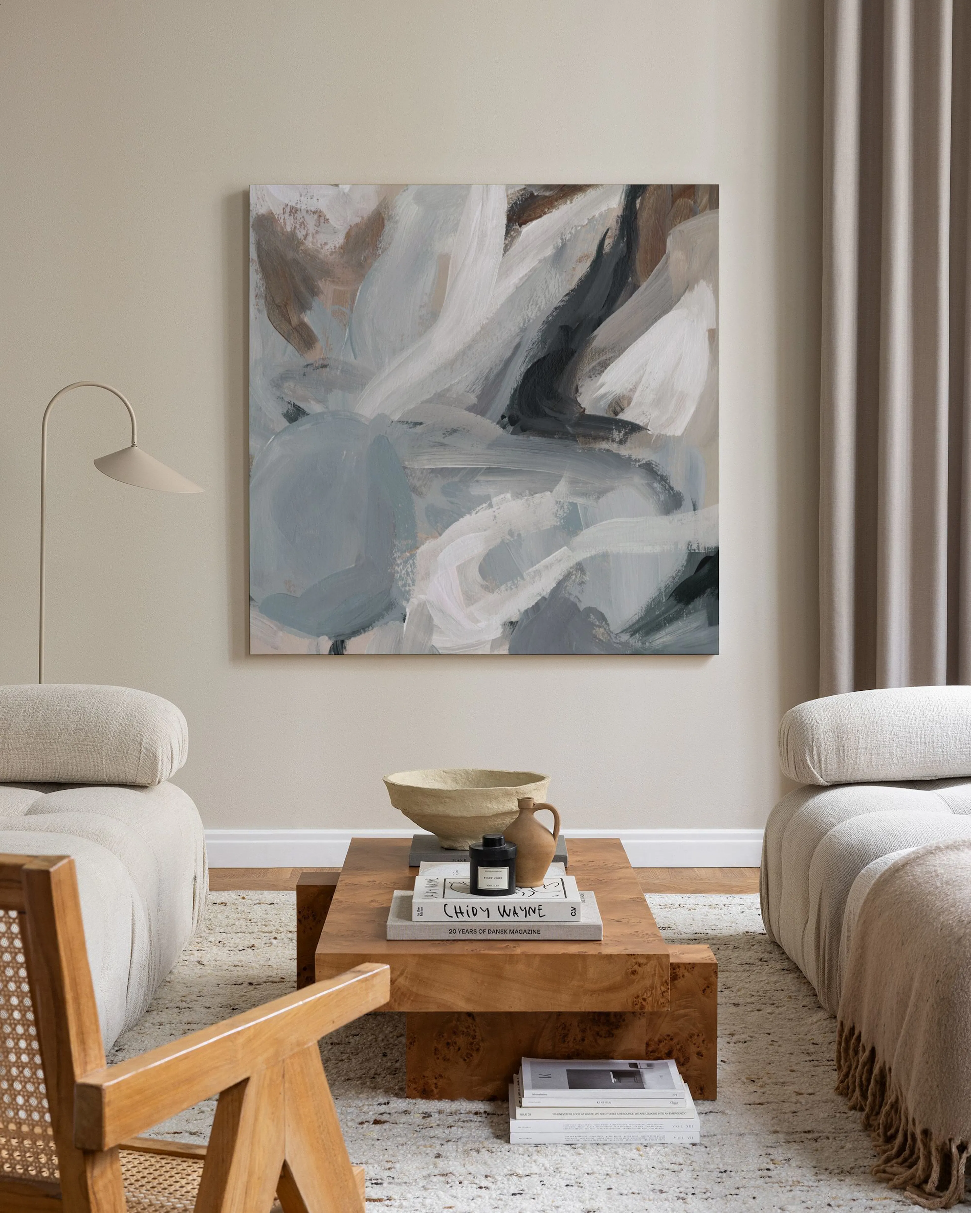 Toile abstraite aux formes organiques gris, blanc cassé et marron, accrochée dans un salon lumineux.