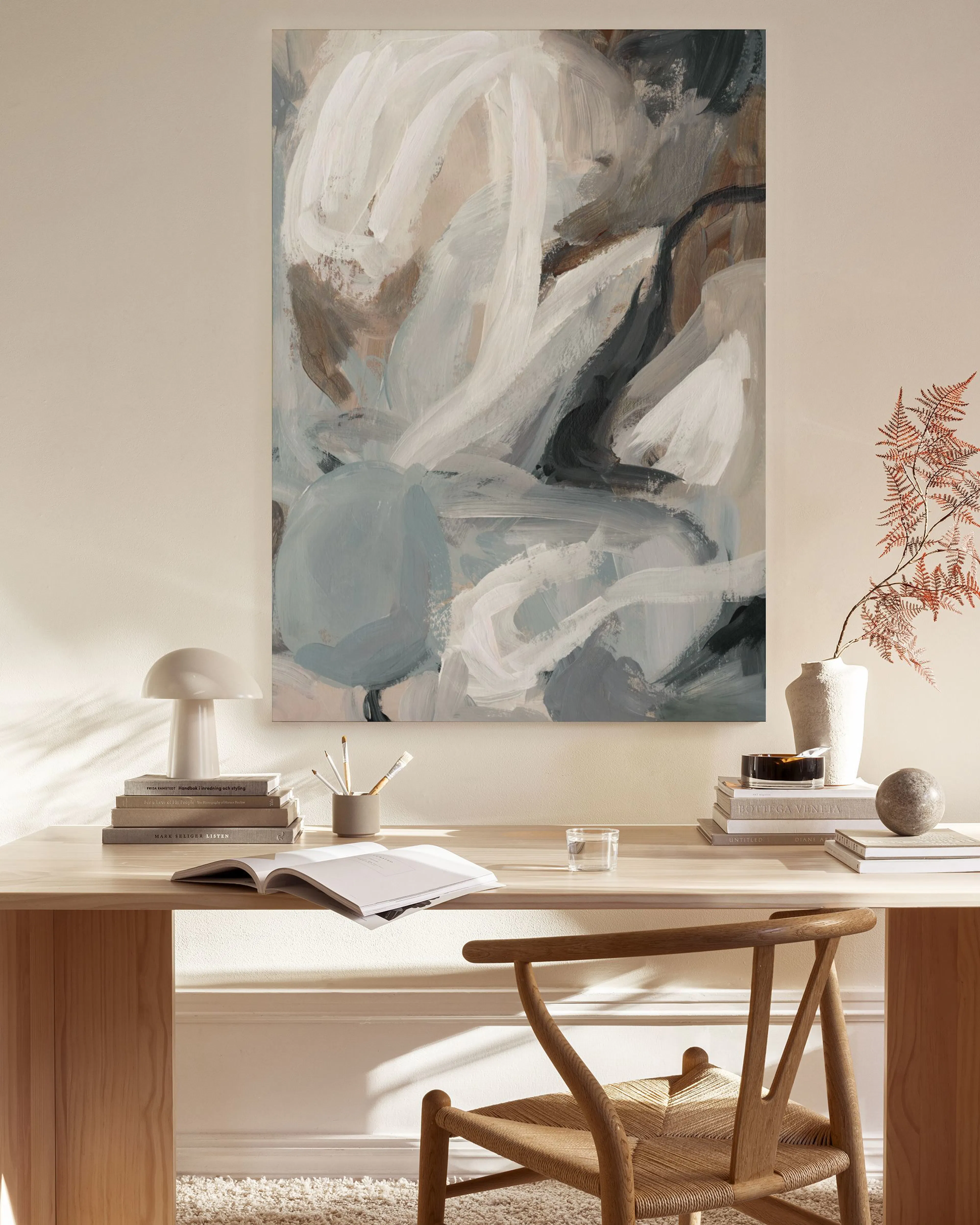 Lienzo abstracto con formas orgánicas en tonos blanco, beige, gris y marrón oscuro, colgando en una sala moderna.