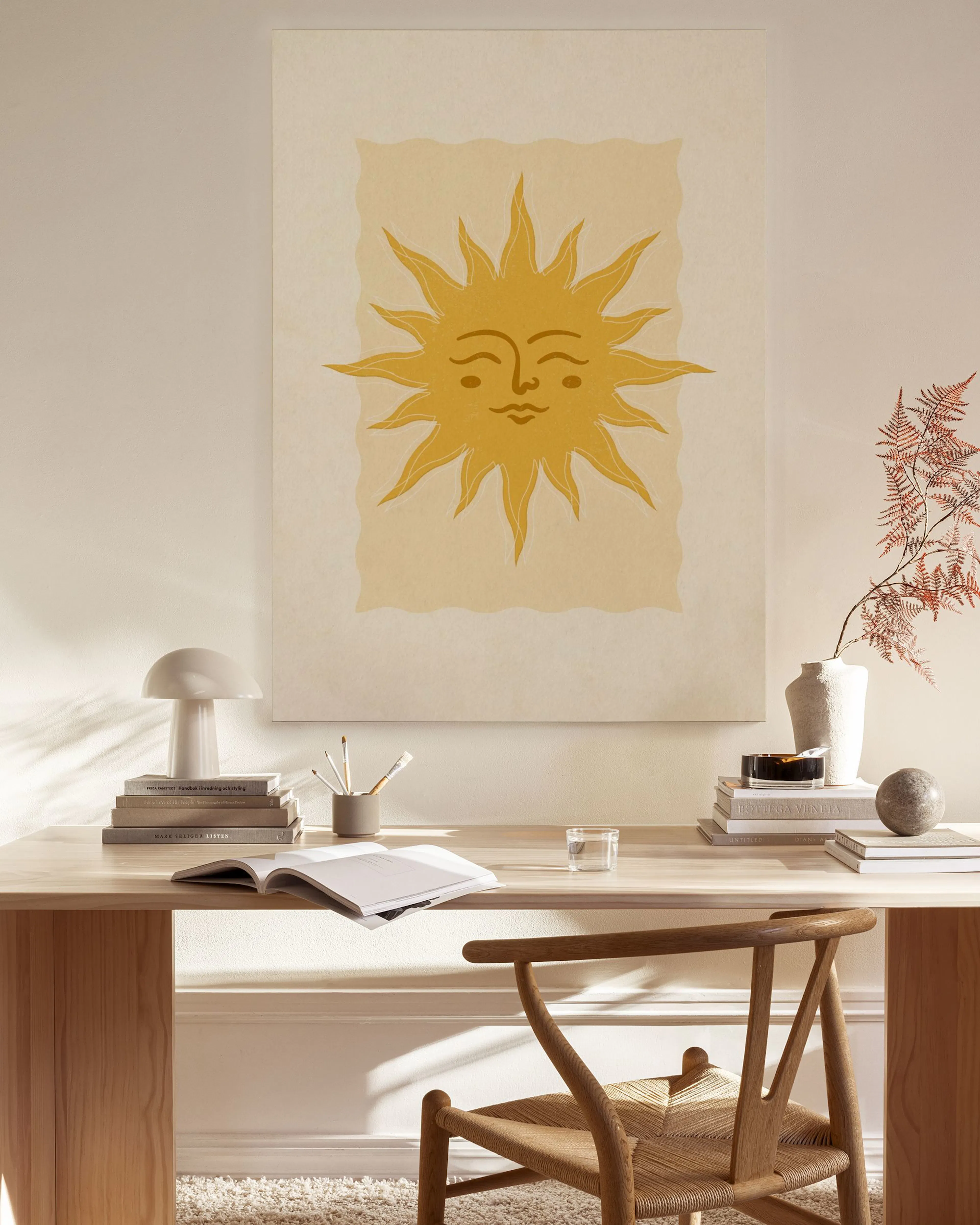 Leinwandbild mit einer gelben Sonne mit Gesicht und Strahlen auf beigem Hintergrund, hängend im Wohnzimmer über einem Sideboard.