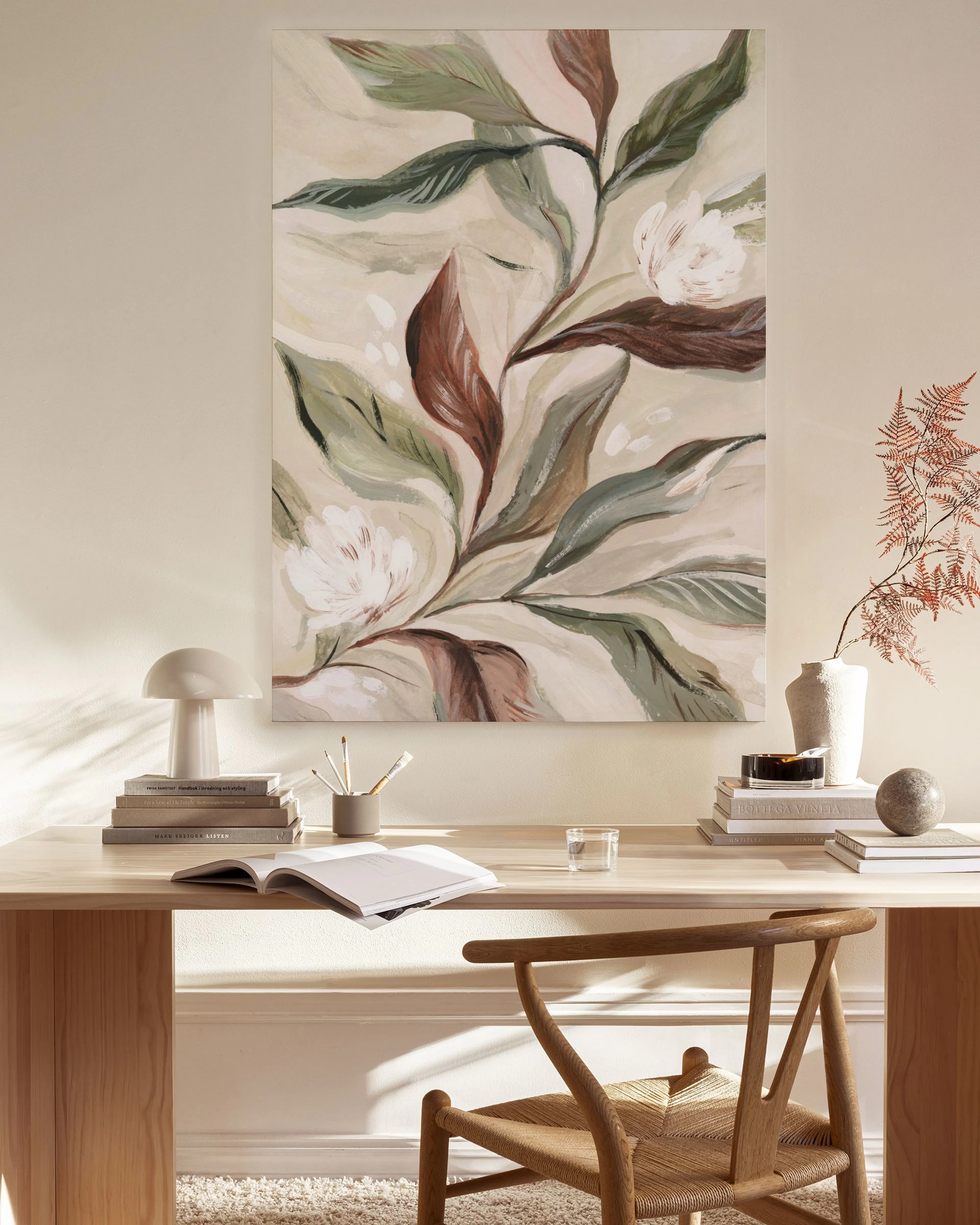 A canvas print of white magnolia flowers and green and brown leaves, displayed in a bright, minimalist living room.
