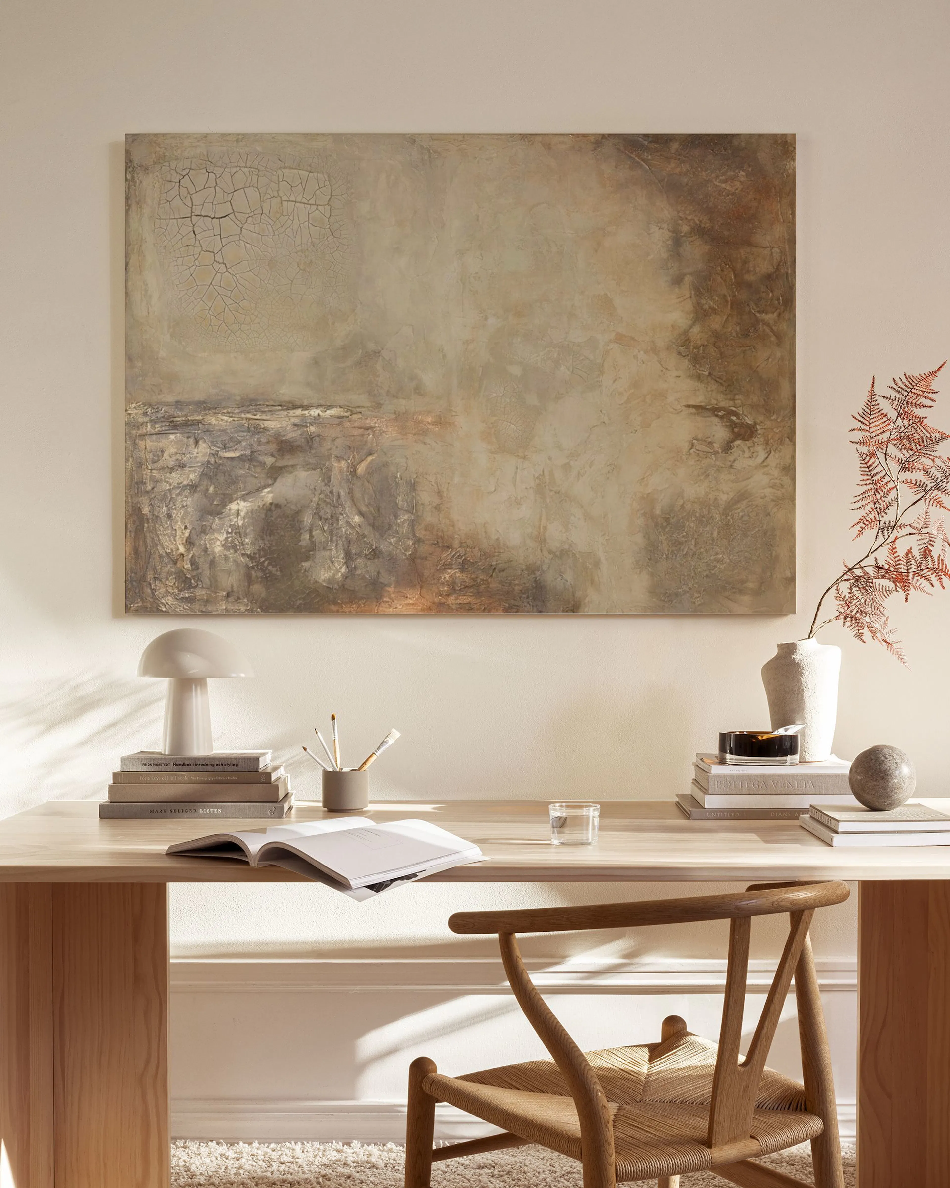 Earthy abstract canvas print with brown, beige, and white tones, hanging above a wooden console in a minimalist living room.