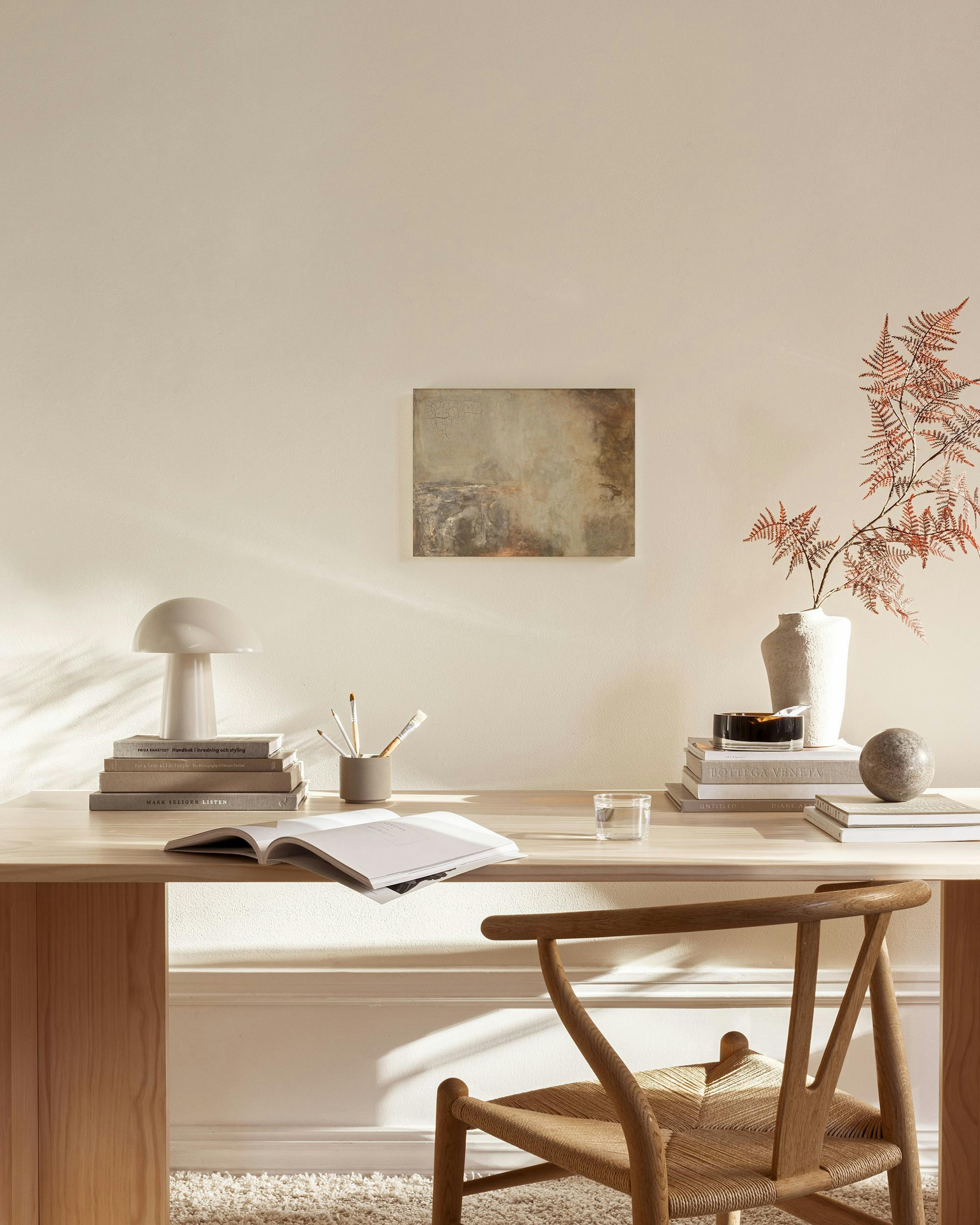 Toile aux tons terreux de gris, beige et brun, suspendue au-dessus dun meuble bas dans un salon moderne.