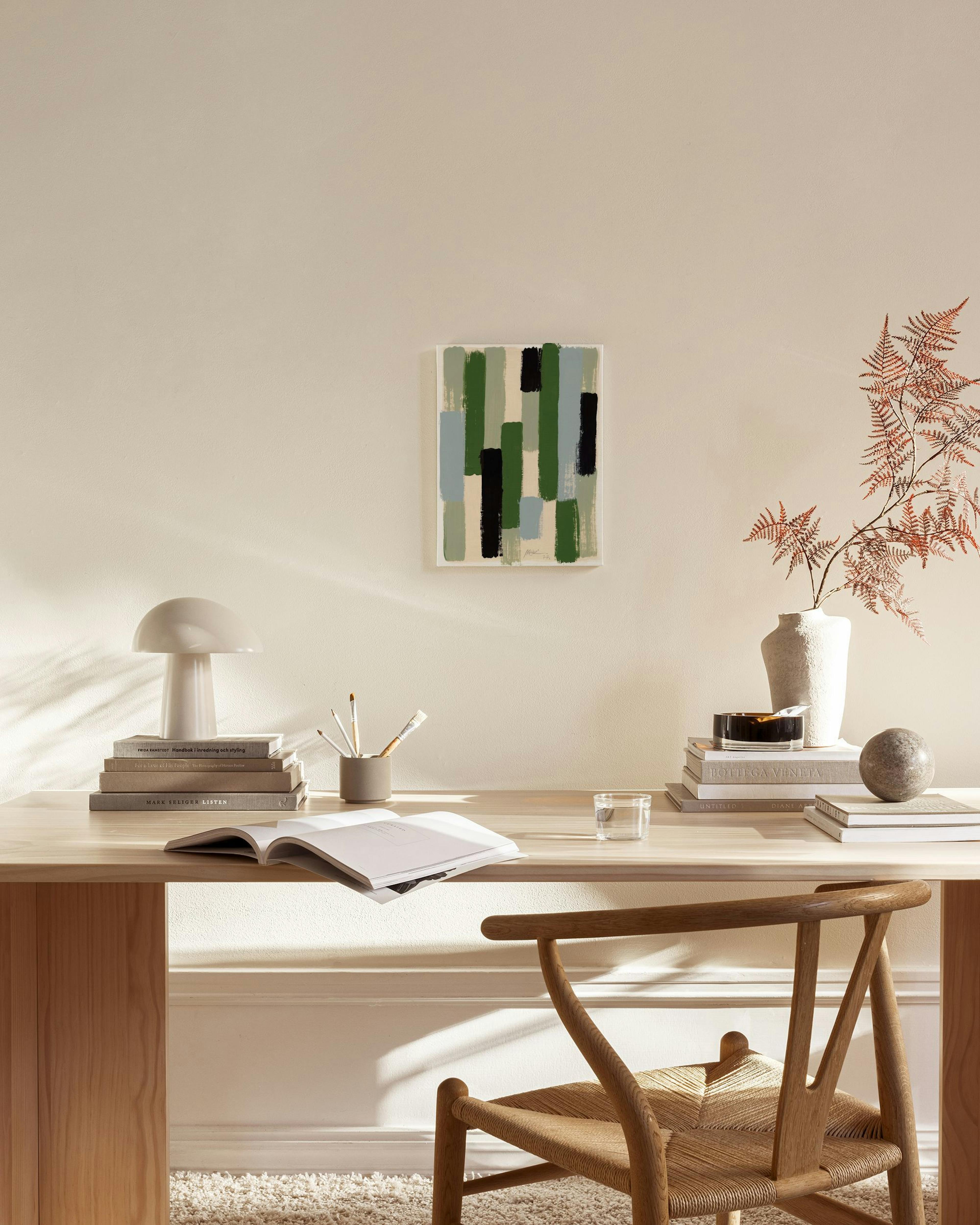 Toile abstraite avec des coups de pinceau vert, bleu, noir et beige, accrochée dans un salon lumineux au-dessus dun banc en bois