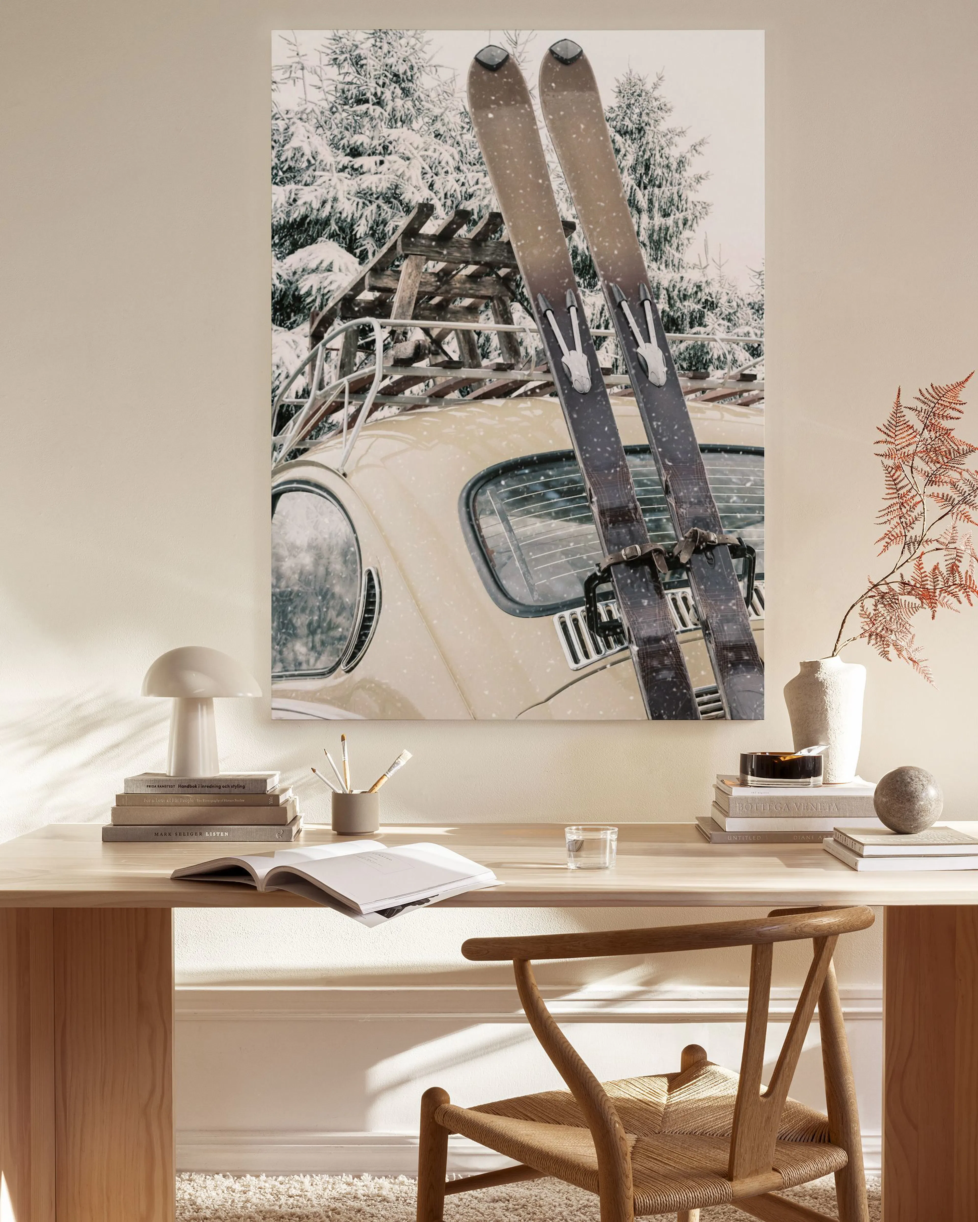 A canvas print of a vintage car with skis on its roof, parked in a snowy forest, displayed in a modern living room.
