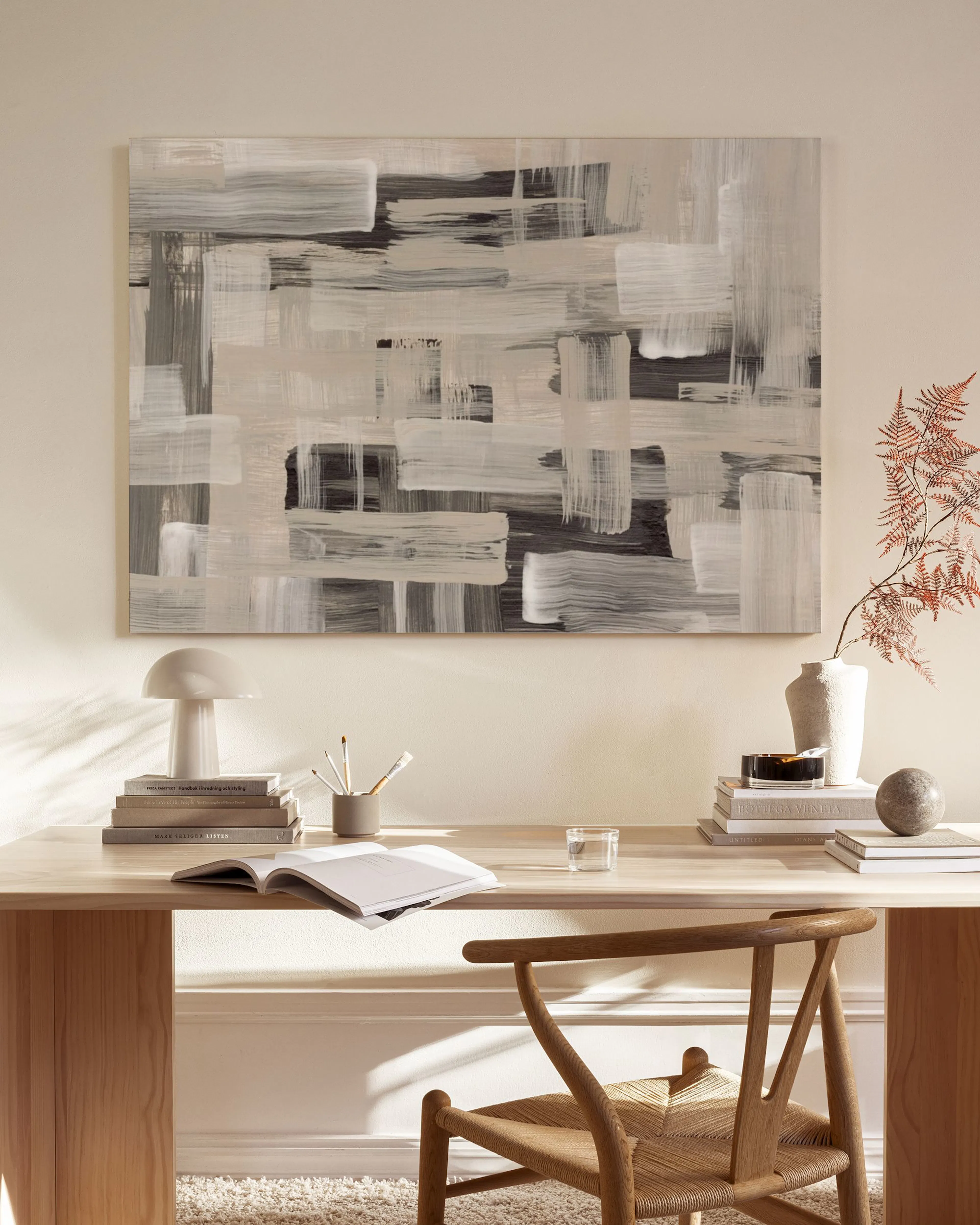 Toile abstraite noir, blanc et beige aux coups de pinceau horizontaux, accentuant un salon neutre et minimaliste.