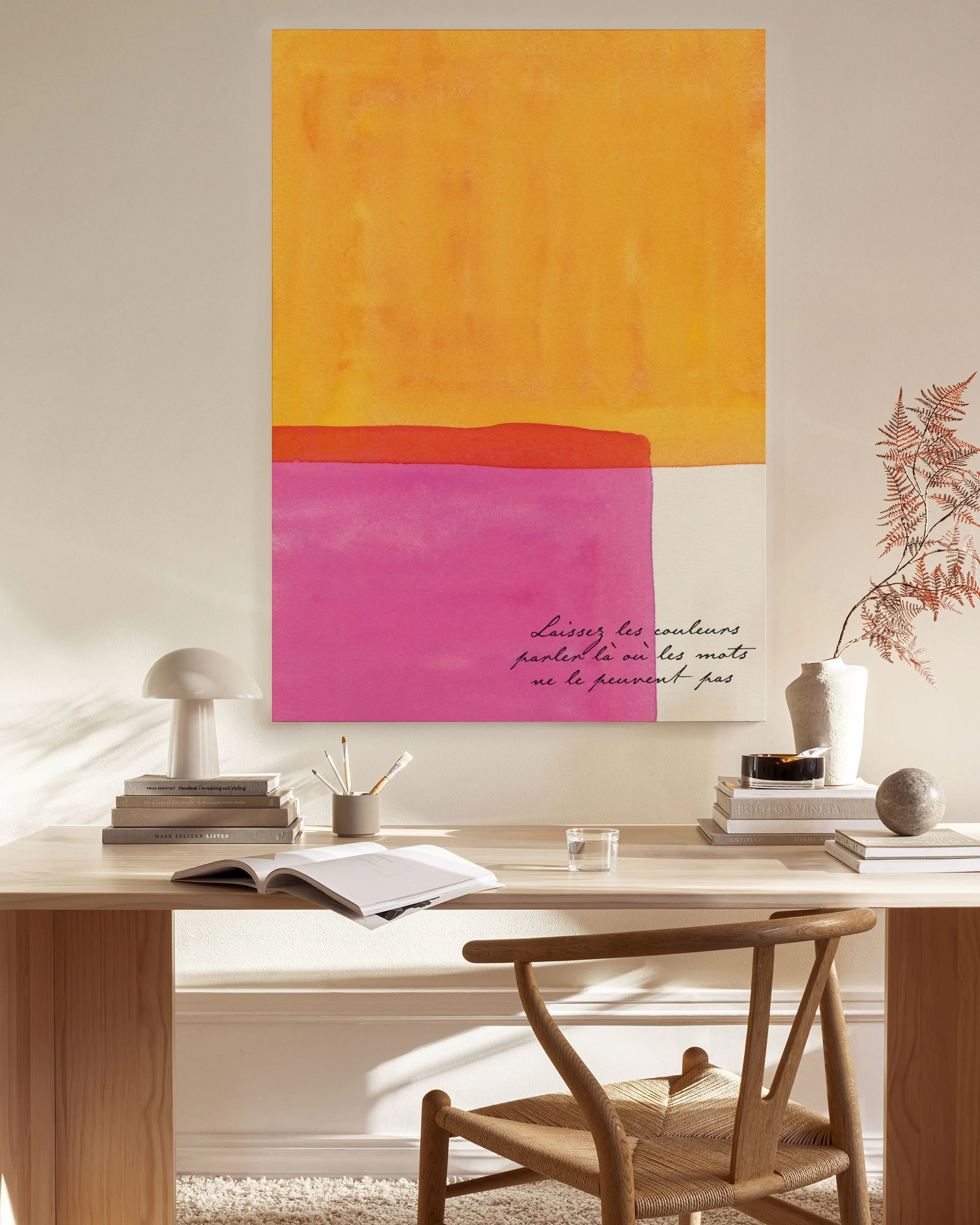 Abstraktes Leinwandbild mit gelben und pinken Farbflächen, Schriftzug, hängt in einem modernen Wohnzimmer über einem Sideboard.