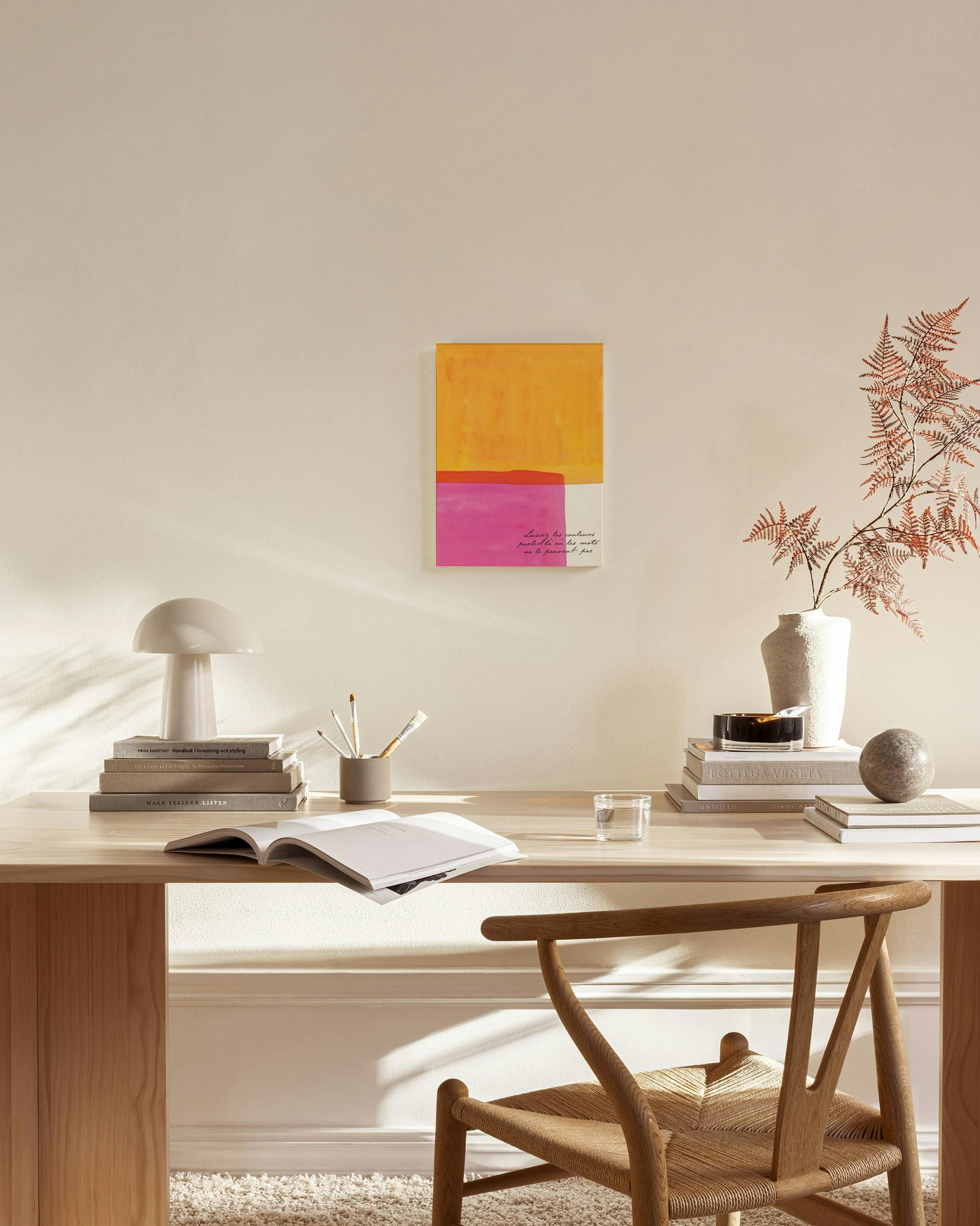 Abstraktný obraz na plátne v odtieňoch oranžovej, ružovej a bielej s textom, visiaci v modernom obývacom priestore.