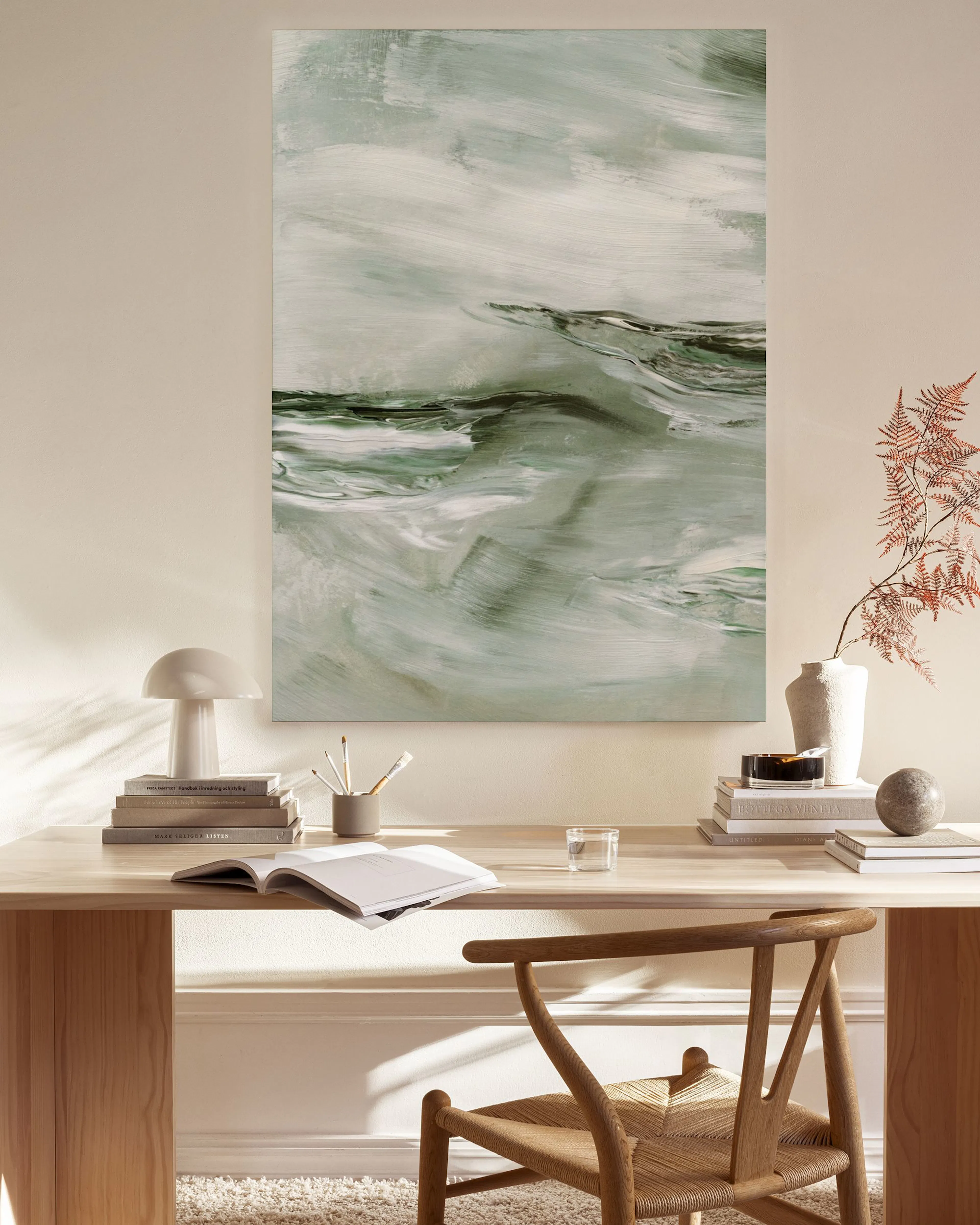 Abstract canvas print with sage green and white brushstrokes, hanging above a wooden console table in a minimalist living room.