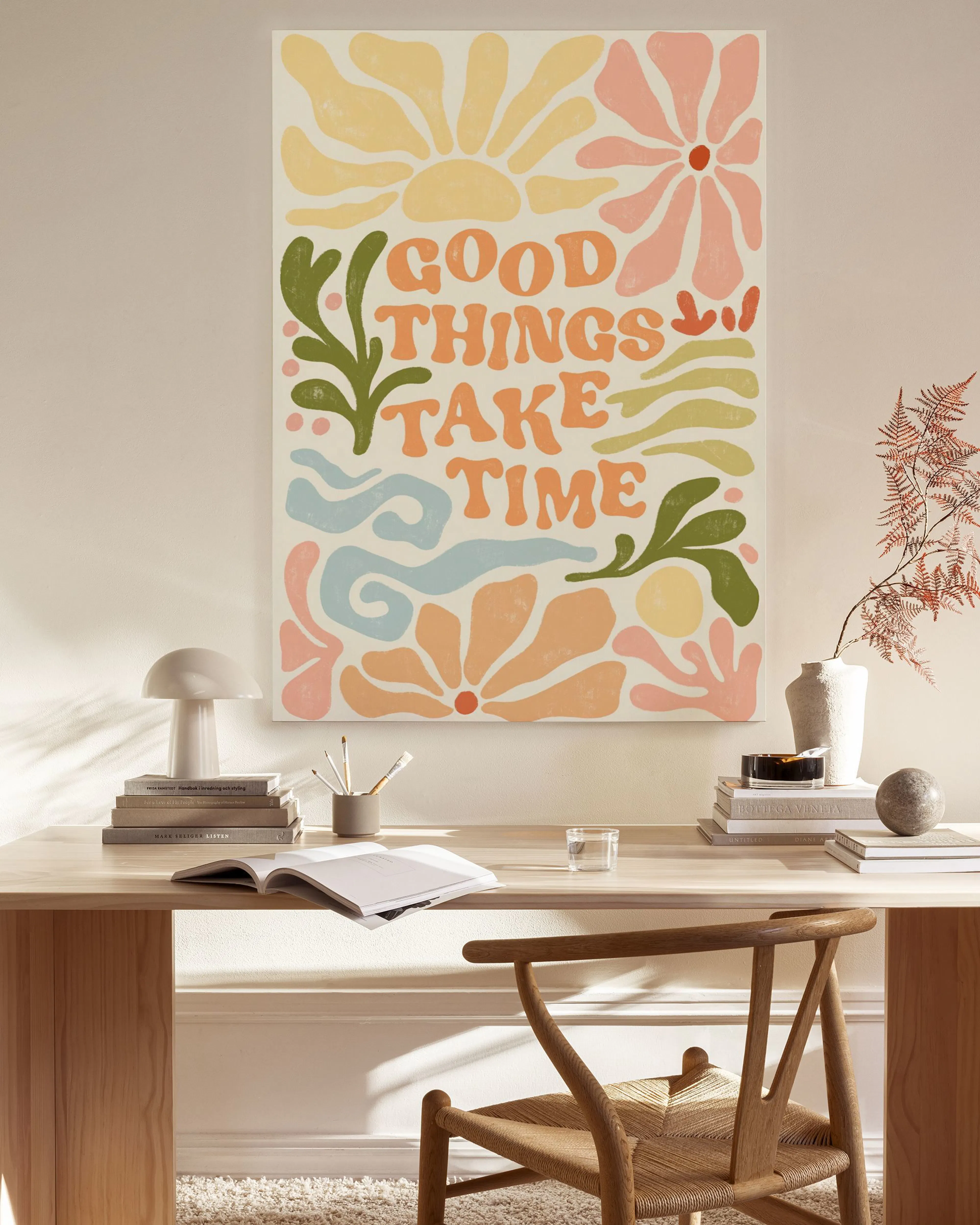 A vibrant Good Things Take Time canvas print with colourful sun, flowers, and leaves, hanging in a modern living room.