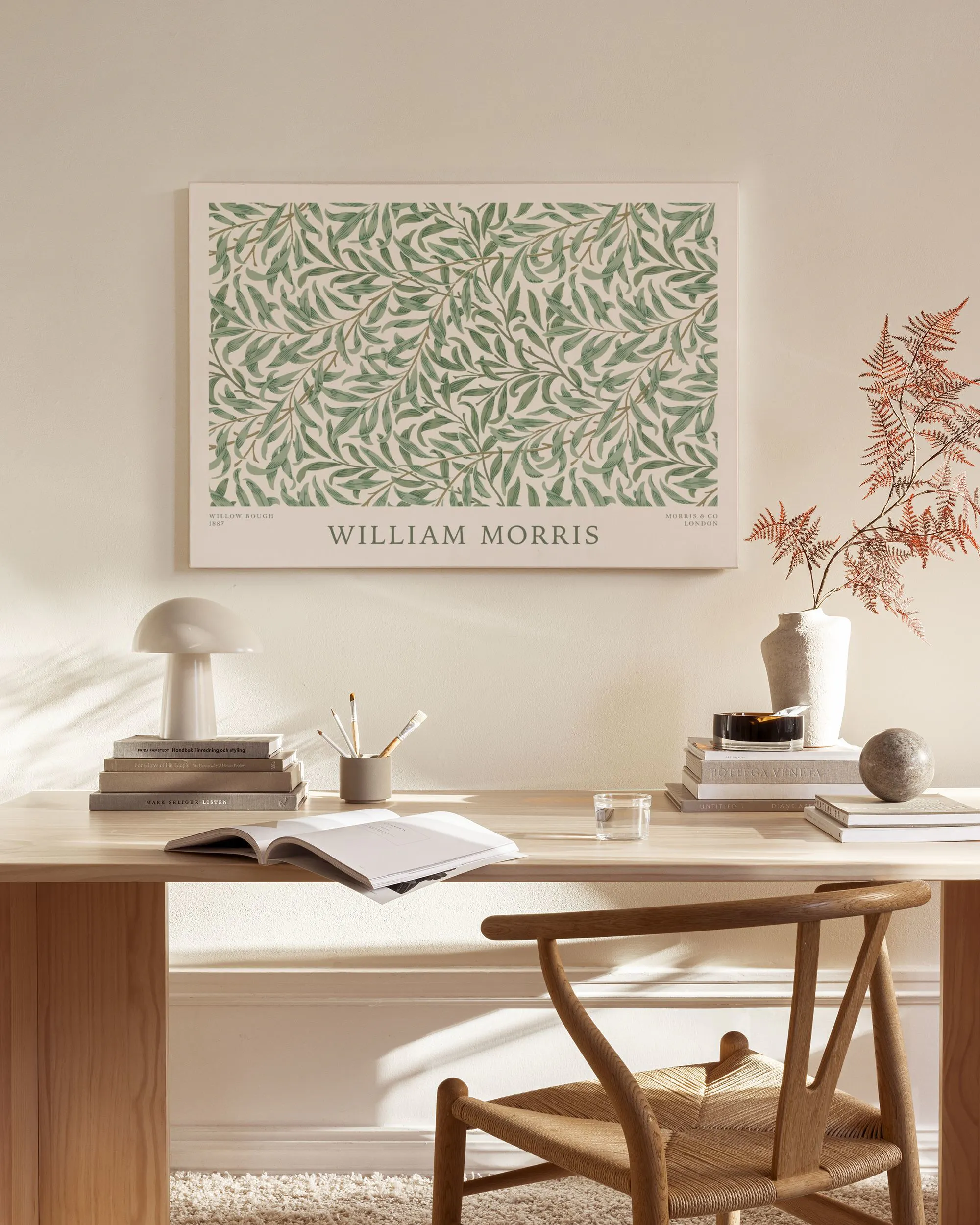 William Morris lærred med grønne blade på lys baggrund, hængende i en stue over en træbænk.