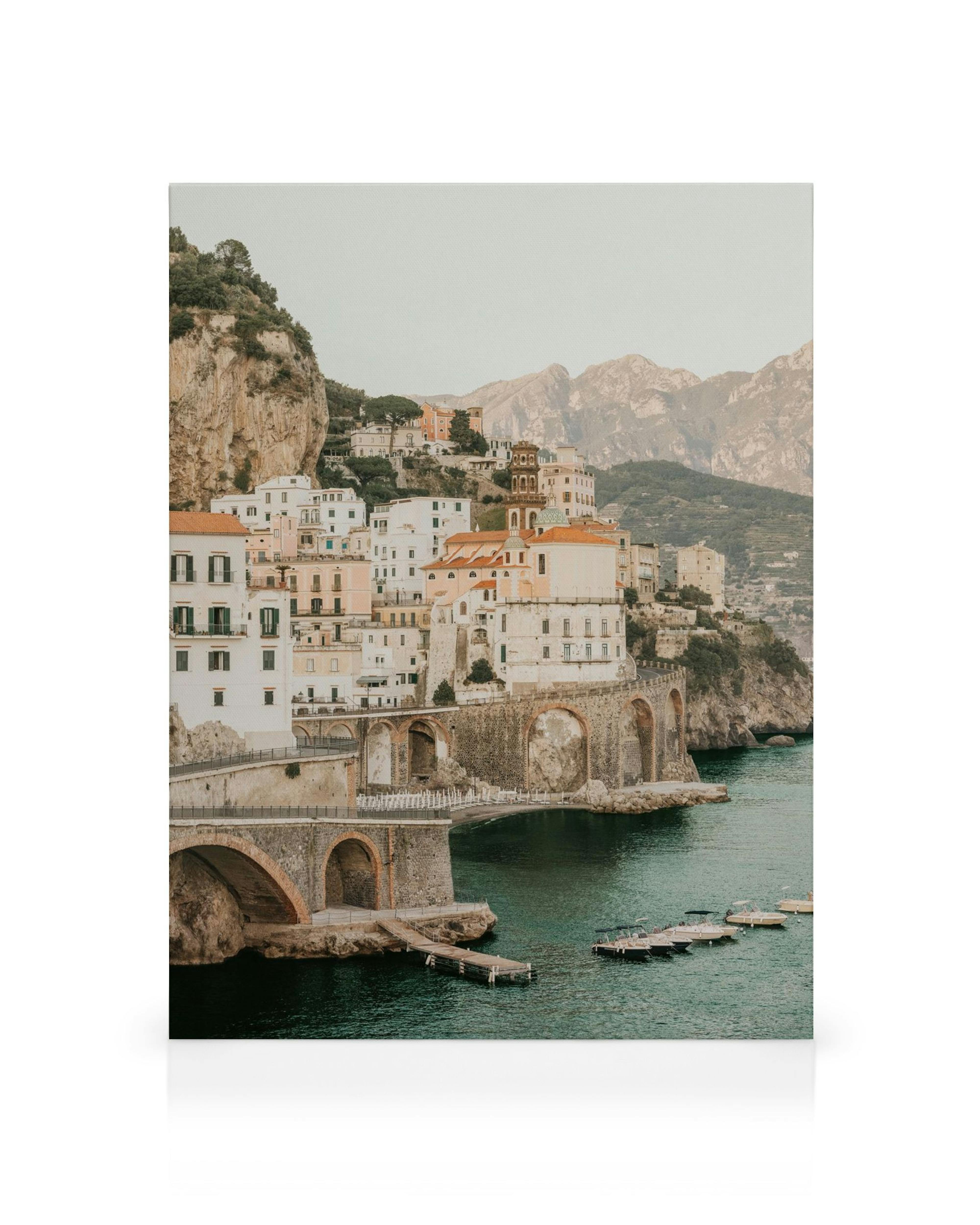 Bella Amalfi canvas: kustscène met kleurrijke gebouwen, gebogen brug en boten in blauw water.
