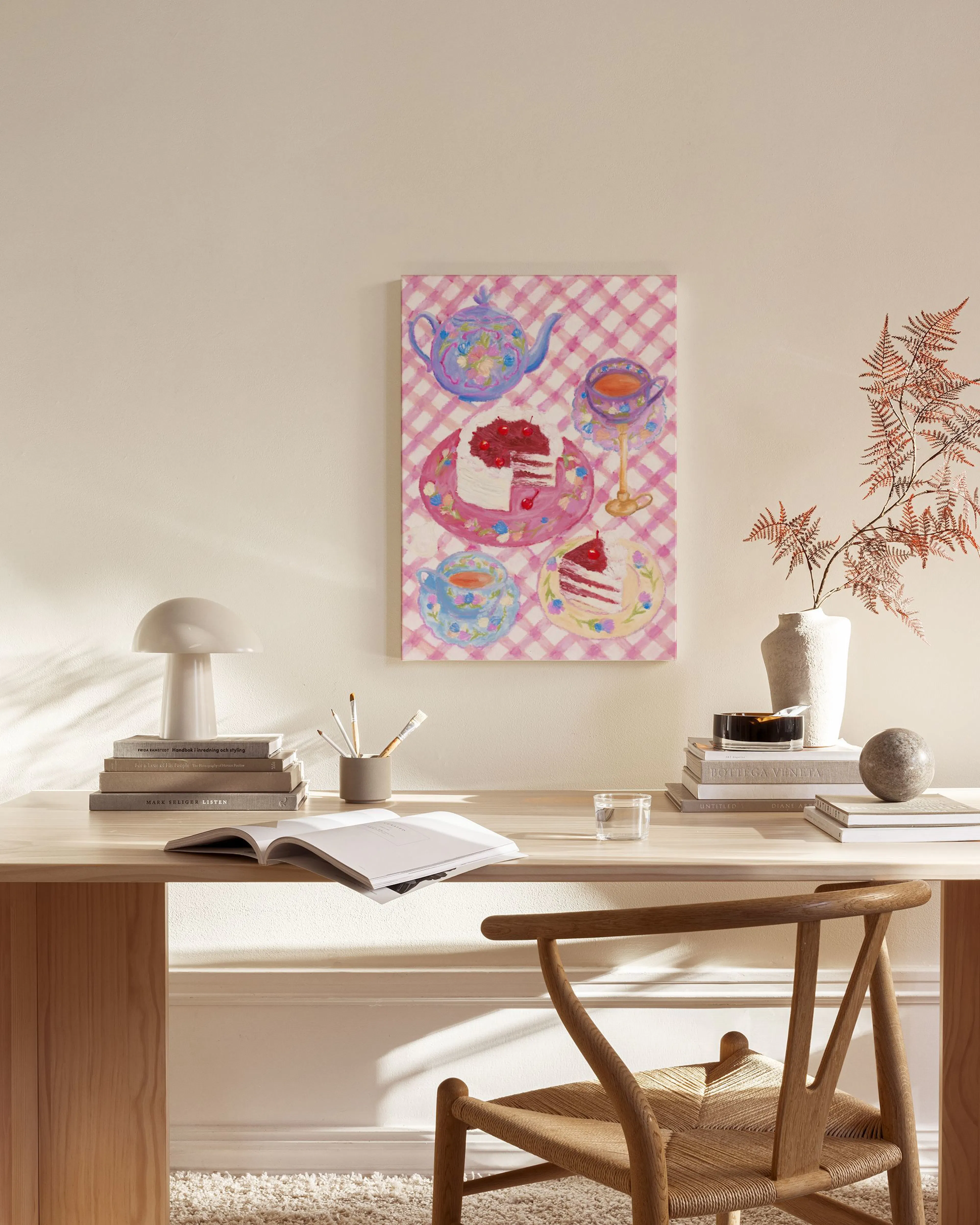 Lienzo con ilustración de tetera, tazas y trozos de tarta sobre mantel de cuadros rosas, colgado en salón moderno.