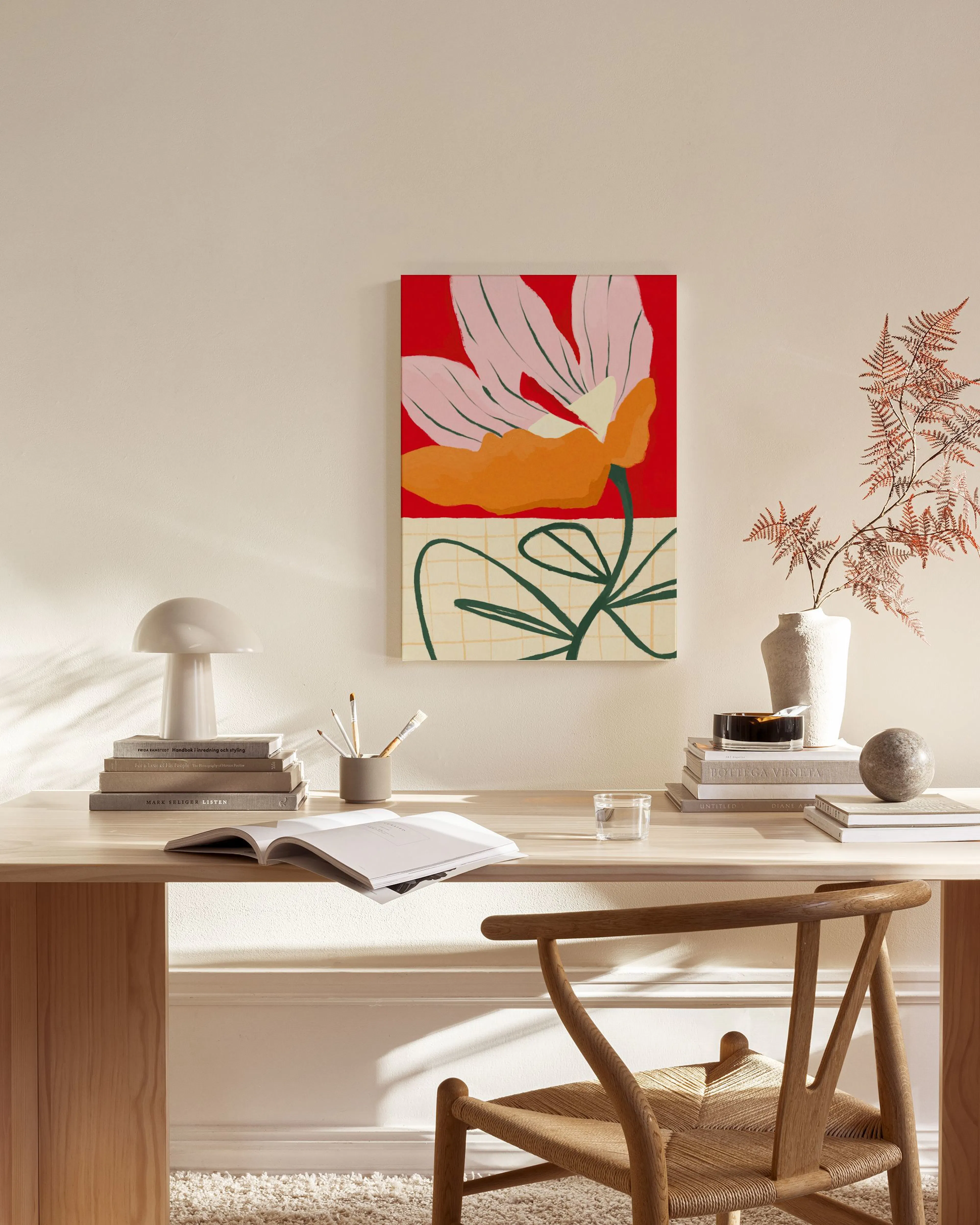 Stampa su tela con fiore stilizzato rosa e arancione su sfondo rosso, appesa in un soggiorno moderno.