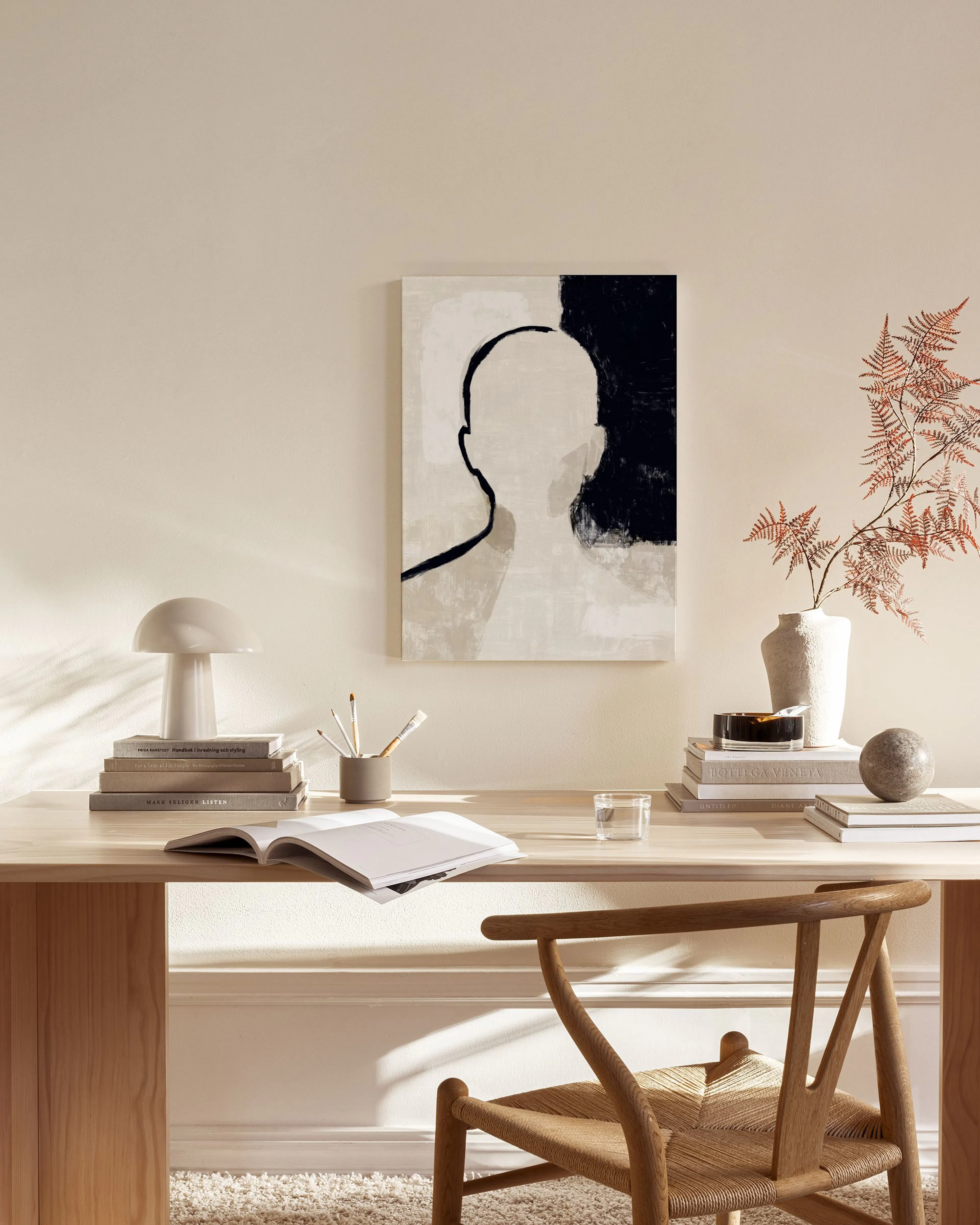Toile abstraite en noir, beige et blanc, représentant une silhouette humaine, dans un salon moderne et lumineux.