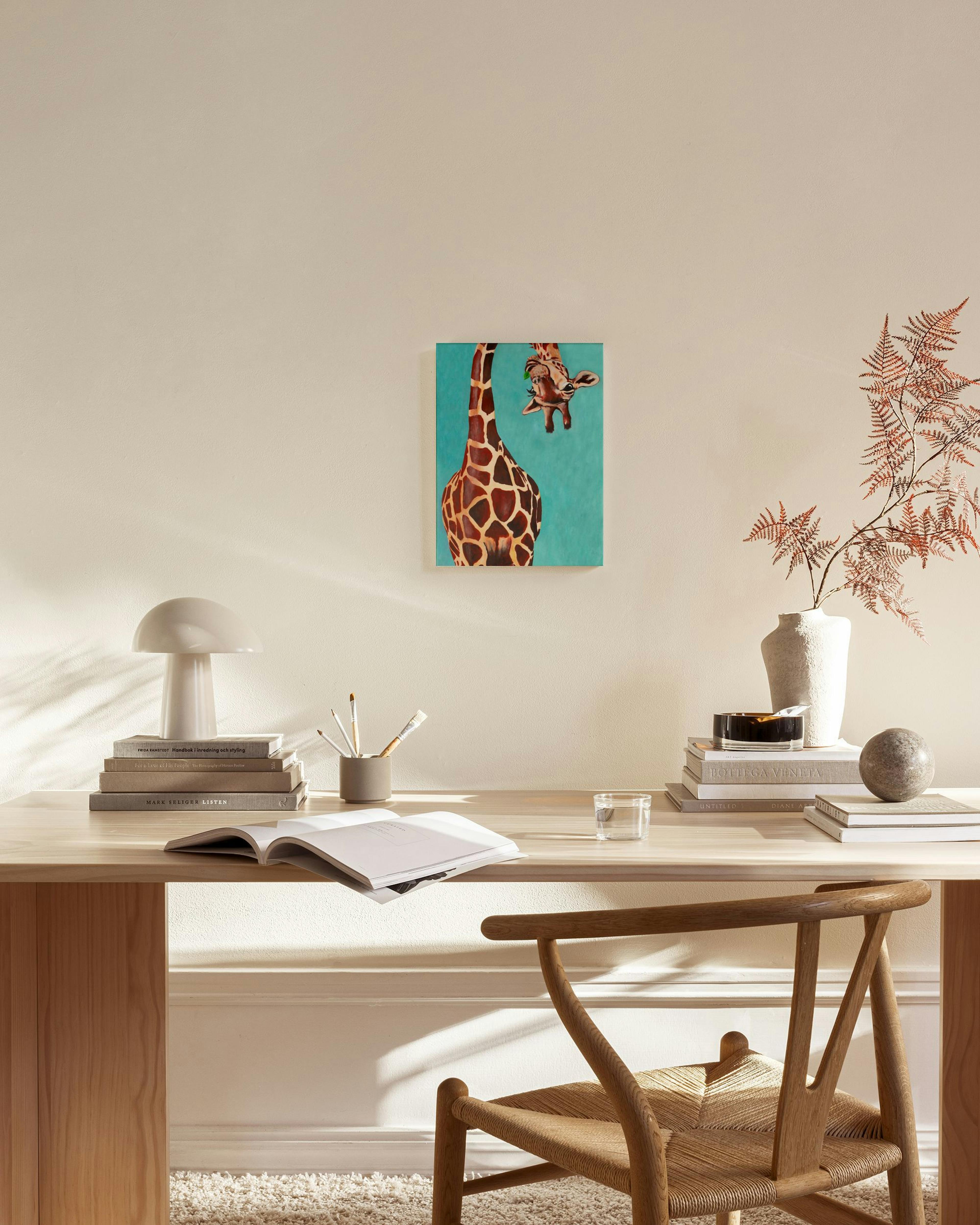 Stampa su tela con giraffa e cucciolo su sfondo turchese, appesa in un salotto moderno.